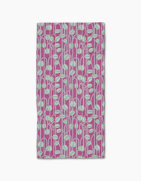 The Magenta Poppy Pods bar towel by Katie OShea is ultra-absorbent and rectangular, featuring a modern, botanical pattern of light blue and white rounded leaf shapes with stems on a magenta background.