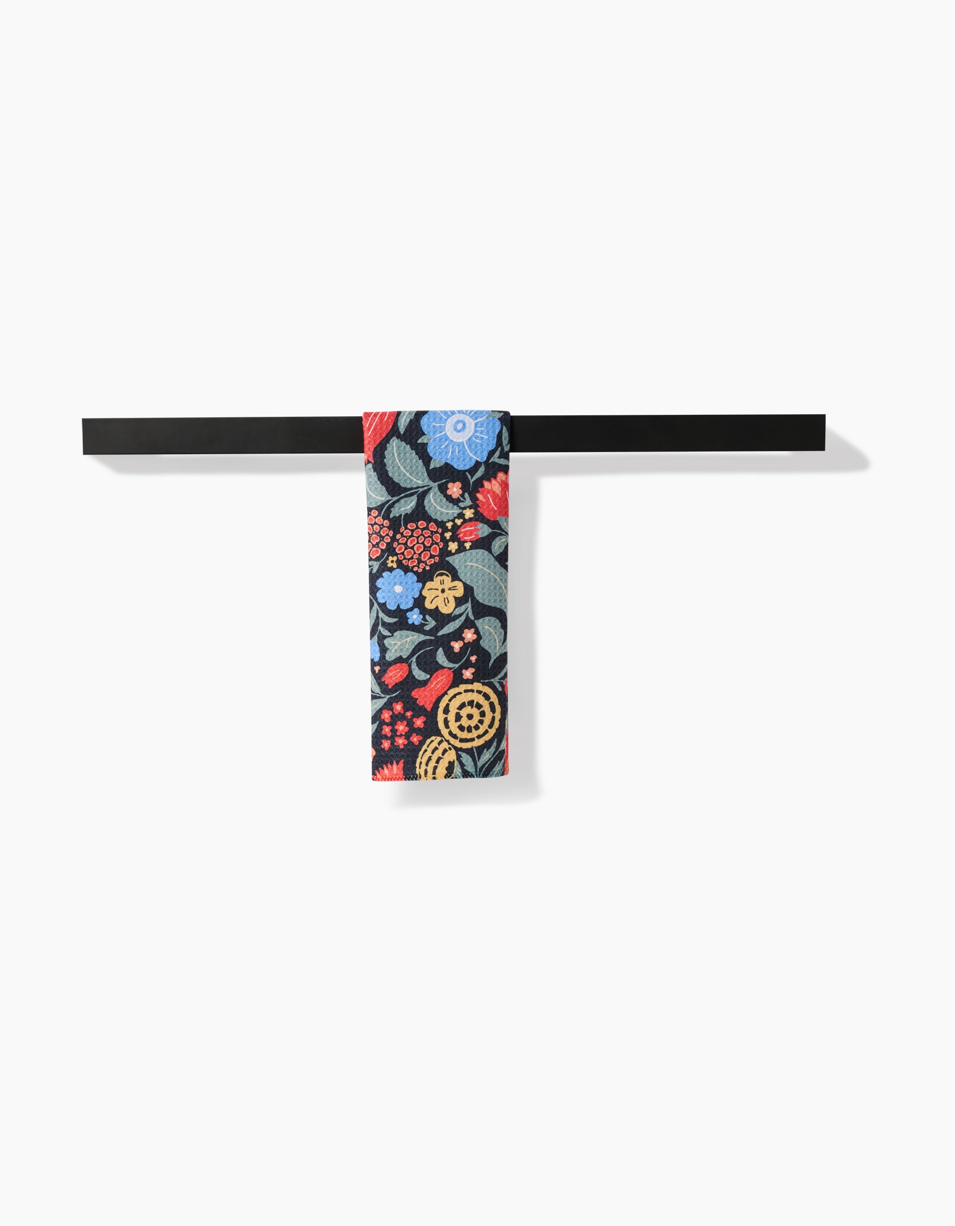 A black horizontal bar holds the Marsh Wren Bar Towel by Danelys Sidron, made from ultra-absorbent Geoweave fabric and featuring red, blue, yellow, and green floral patterns on a plain white background.