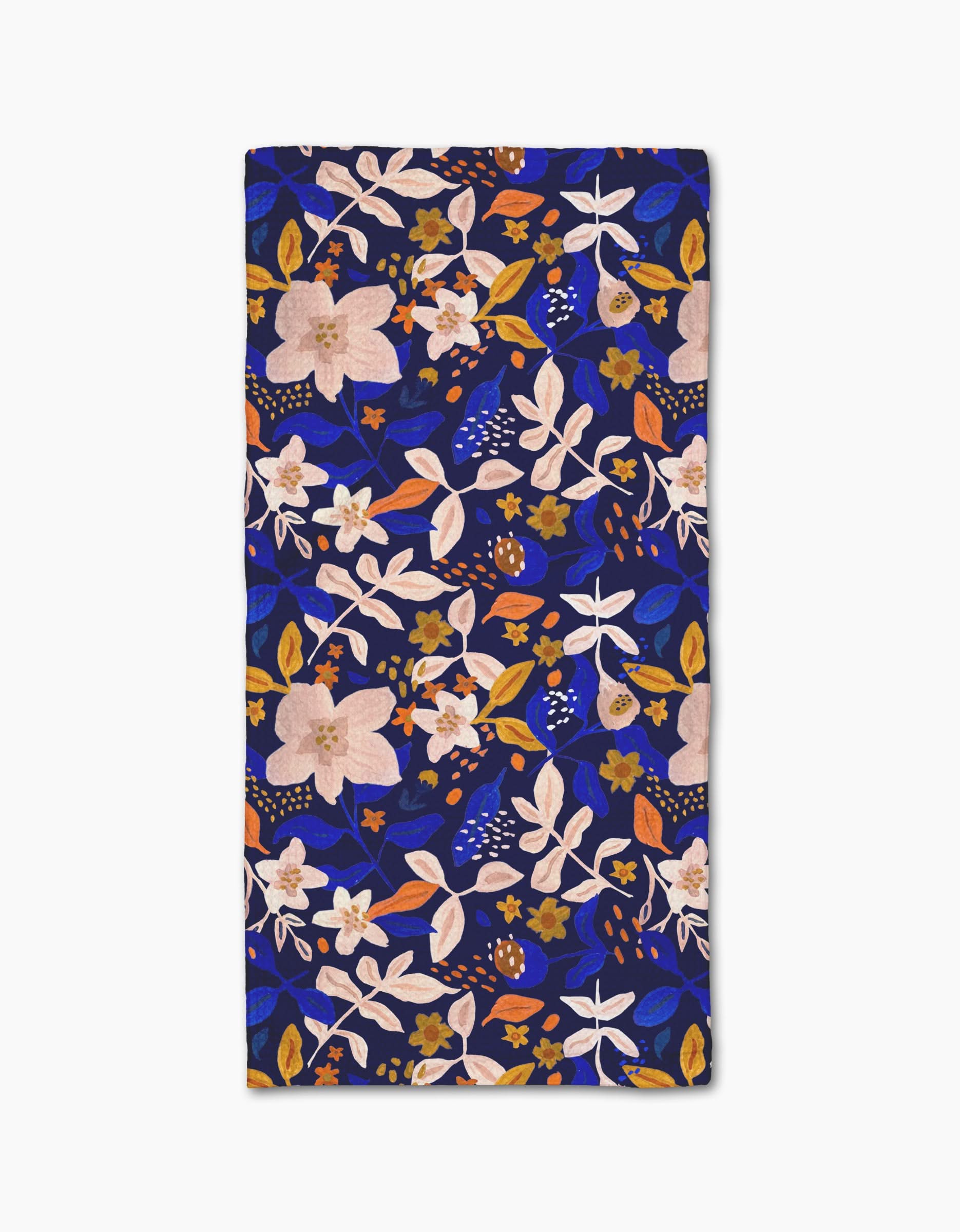 The Nightfall Garden towel by Cottonflower Studio is rectangular, ultra-absorbent, and features a bold floral pattern with pink, white, and orange flowers and leaves on a dark blue background.