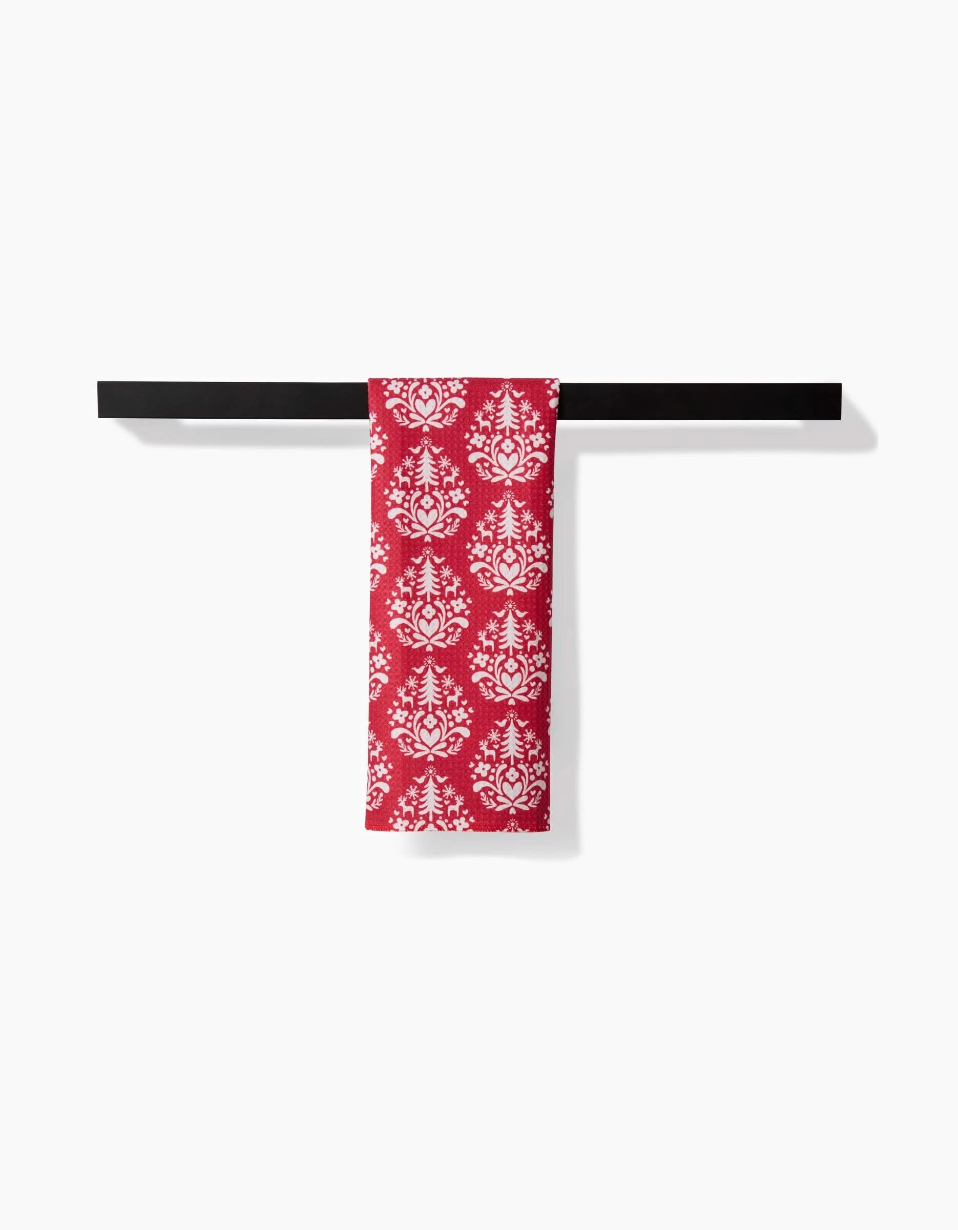 A Kayla Ann Nordic Holiday Stamp Red towel with a white floral pattern is neatly folded over a black towel bar against a plain white background.
