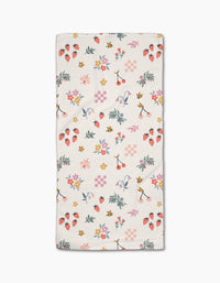The North Meadow Morning Bar Towel by Charlie Rowan Designs features a colorful pattern of strawberries, cherries, bees, flowers, leaves, and shapes in pink, yellow, green, and purple on white—crafted from sustainable recycled materials.