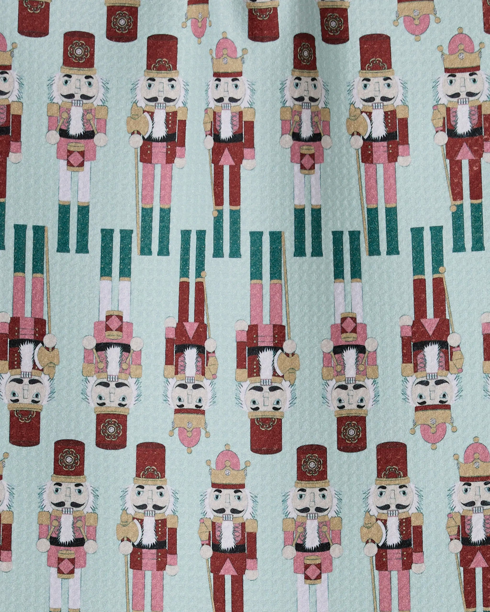 The Geometry Nutcracker March bar towel features rows of colorful nutcracker soldiers in red, gold, and green on a light blue background. The slightly quilted, ultra-absorbent design makes it both stylish and functional.
