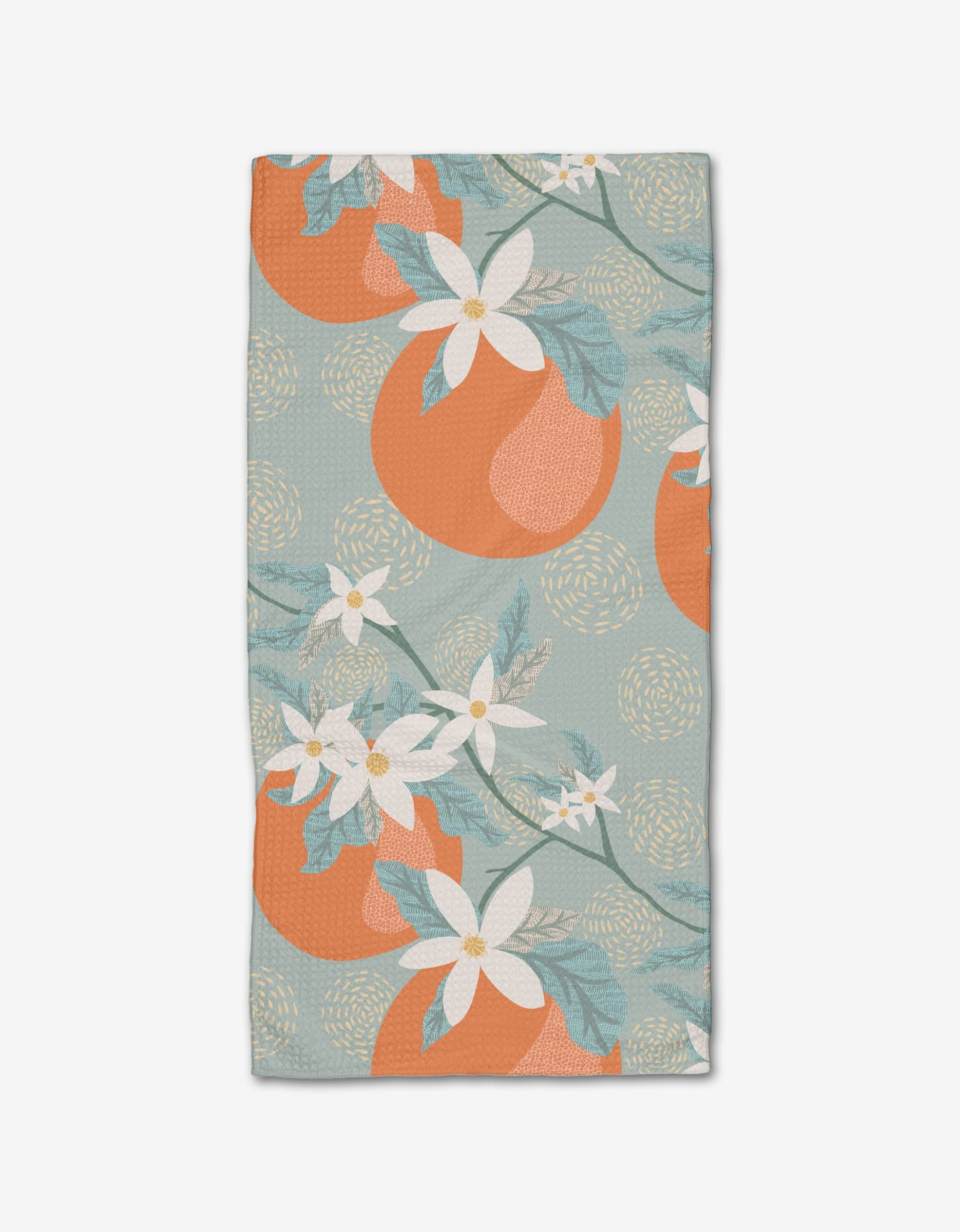 The Orange Blossom Bar Towel by Julianne Haness features large oranges, white flowers, and green leaves on a light blue backdrop with circles. Crafted from ultra-absorbent Geoweave fabric for superior performance.