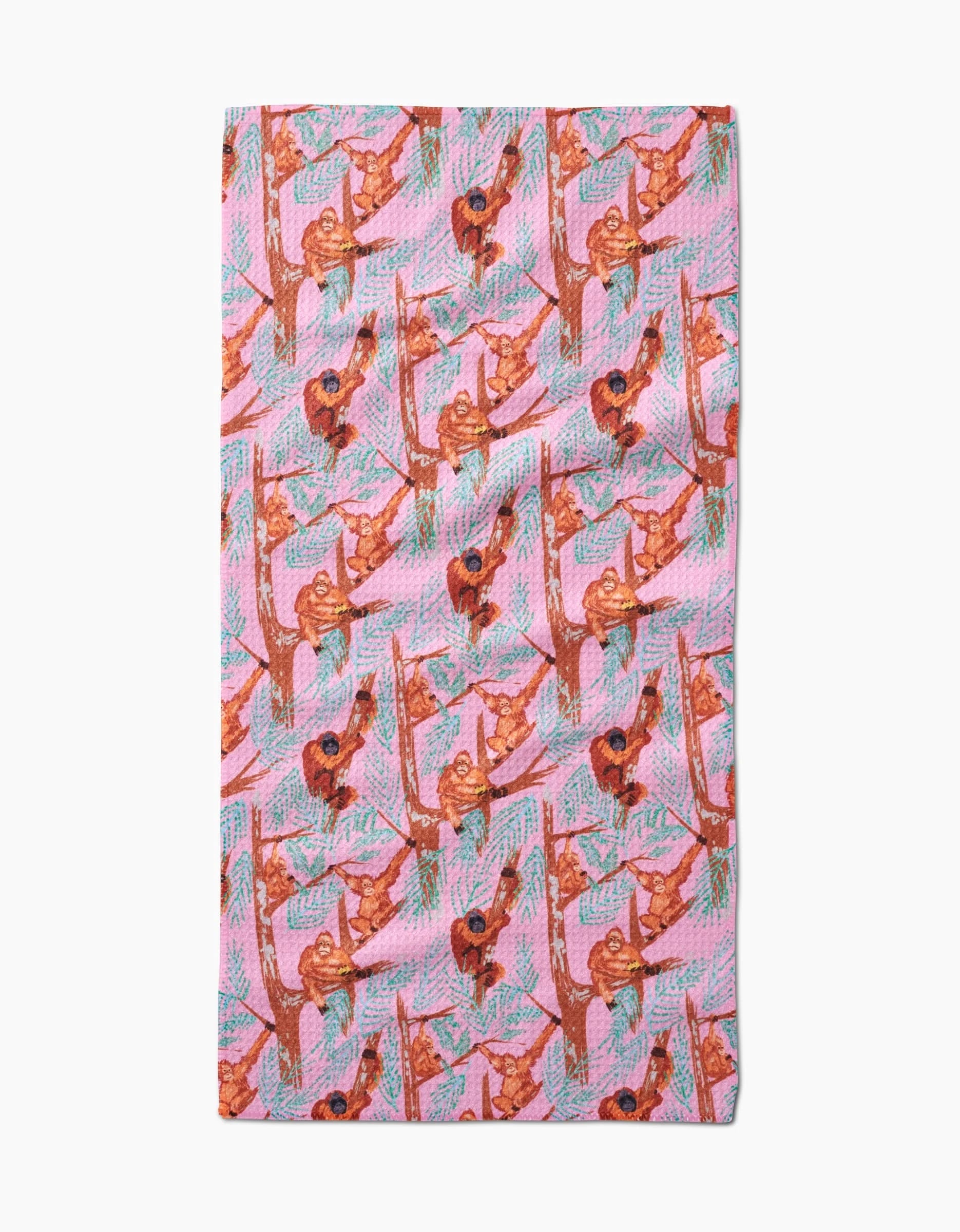 The Orangutan Clan bar towel by Elisabeth Wing showcases a pink design with illustrated brown orangutans hanging from green and brown branches, made from recycled materials.