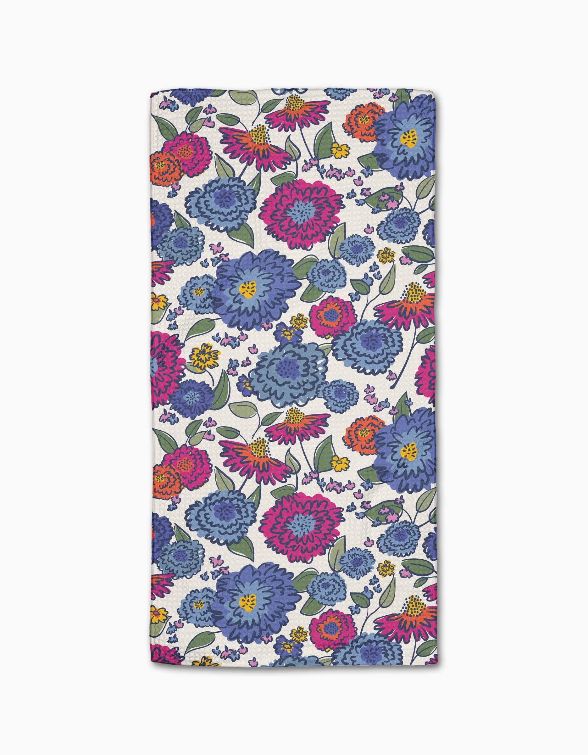 The Painterly Meadow bar towel by Kris Ruff features large blue, pink, and purple flowers with orange and yellow blooms plus green leaves on white Geoweave fabric for superior absorbency.