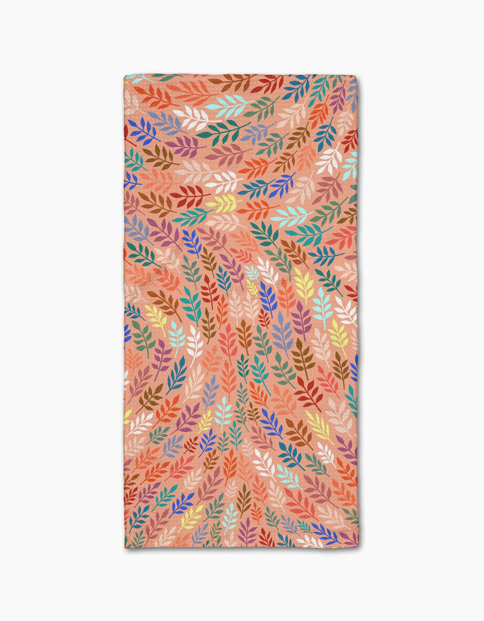 The Rachel Parker Peachy Leaf Swirl towel is rectangular and ultra-absorbent, featuring a light brown background with colorful overlapping leaf patterns in orange, red, green, blue, yellow, and purple.