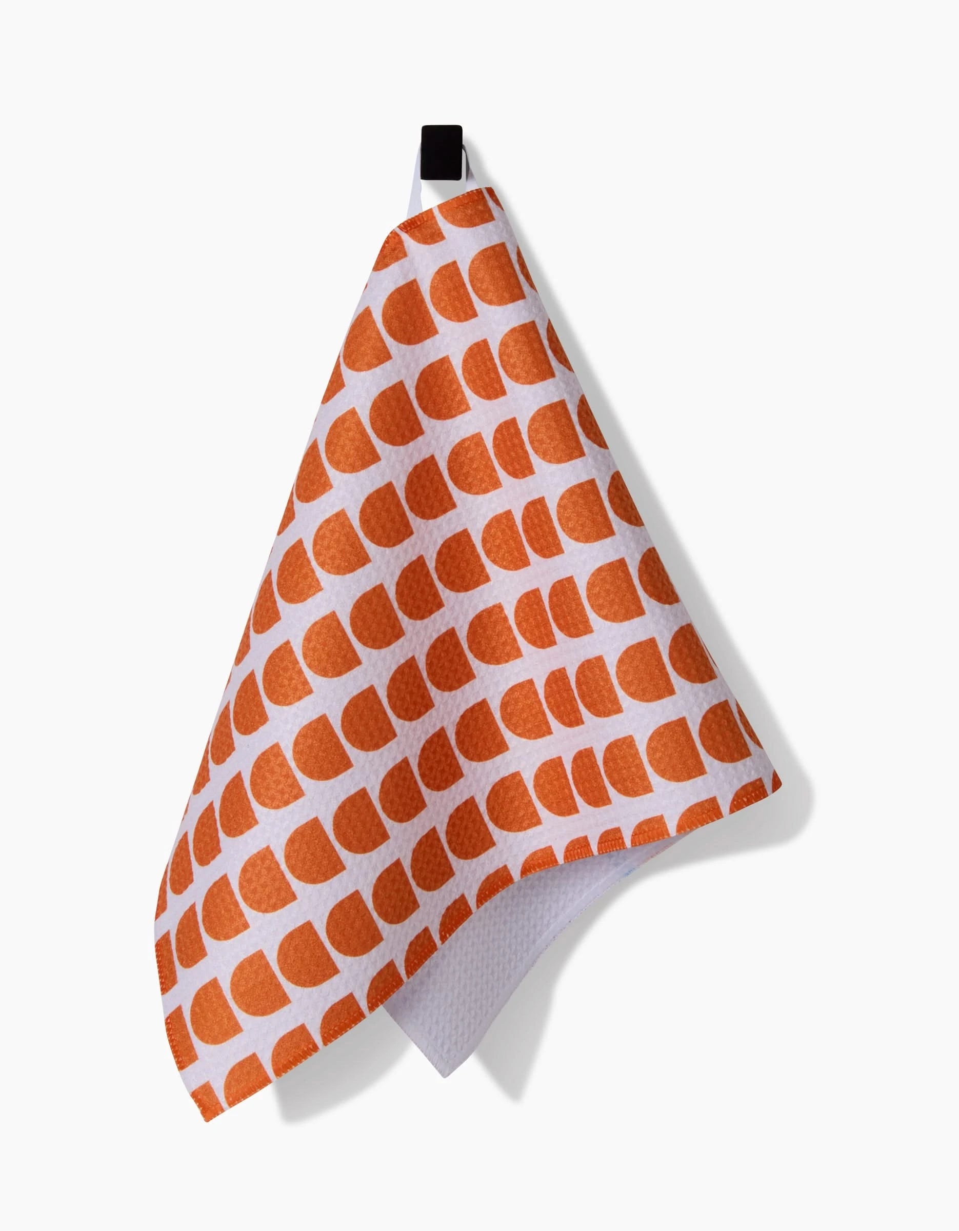 The Happy Hemera Pink Illusion bar towel, featuring a pink semicircle pattern and made from Geoweave fabric, hangs from a black loop against a plain white background.