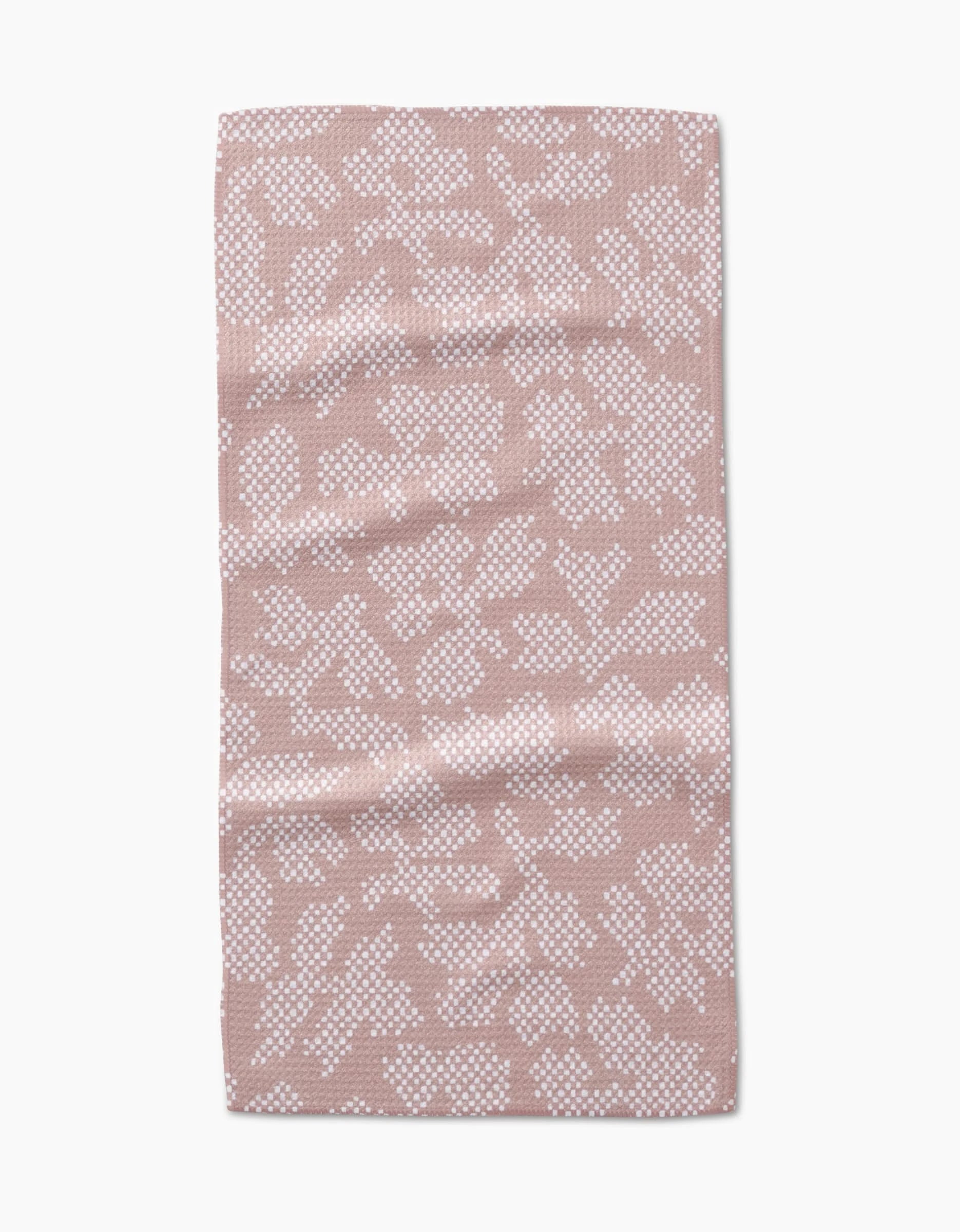 The Studio Jeannot Pixie towel is a rectangular, light pink bar towel with an abstract white dotted pattern, made from soft Geoweave fabric. Gentle creases add a plush, modern touch as it lays flat on a white background.