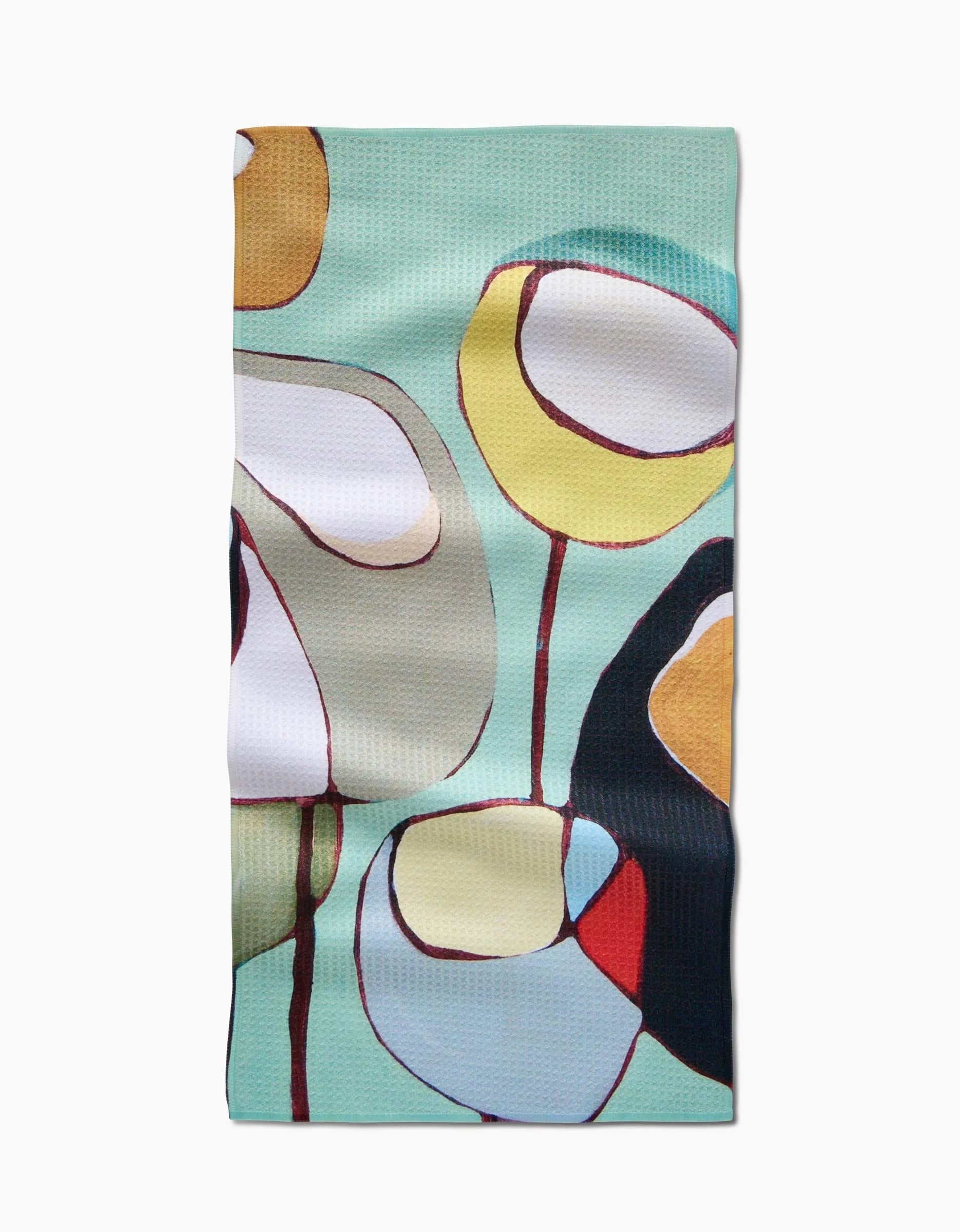 The Poppies on Mint bar towel by Rachel Austin showcases an abstract floral design in yellow, orange, blue, white, and black on a mint background, made from recycled materials.