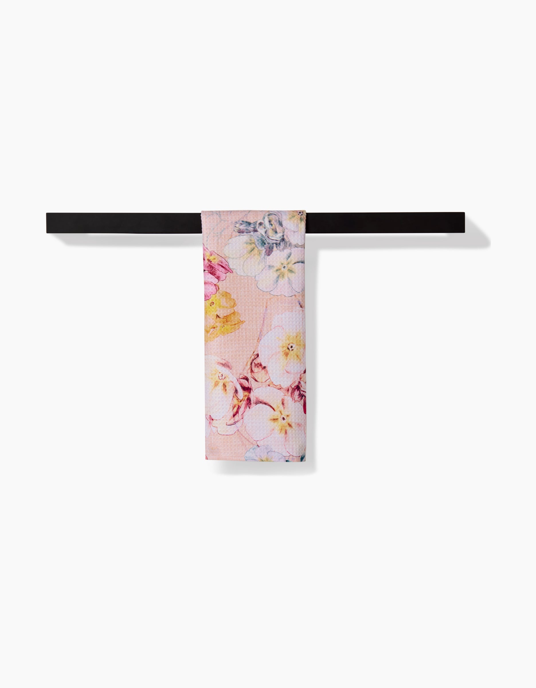 The Pascale Dilger Primroses Bar Towel features a pink Geoweave fabric with yellow and purple floral patterns, hanging over a black bar against a white background. Enjoy superior absorbency and soft texture.