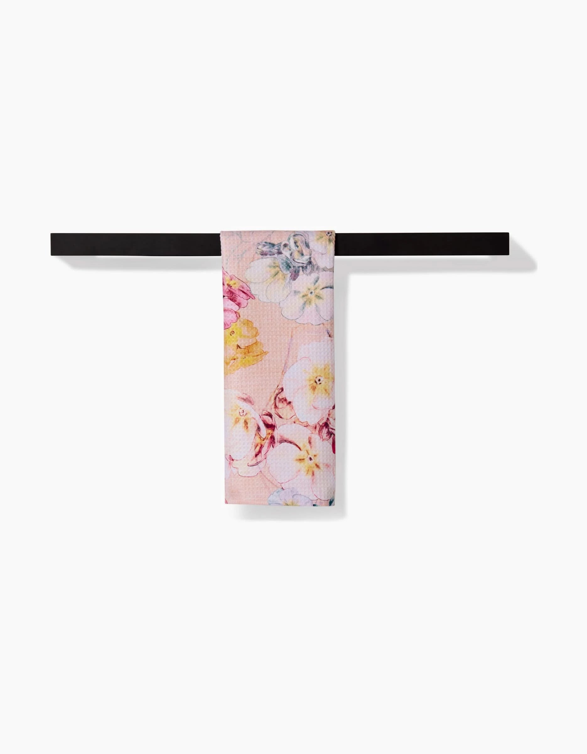 The Pascale Dilger Primroses Bar Towel features a pink Geoweave fabric with yellow and purple floral patterns, hanging over a black bar against a white background. Enjoy superior absorbency and soft texture.
