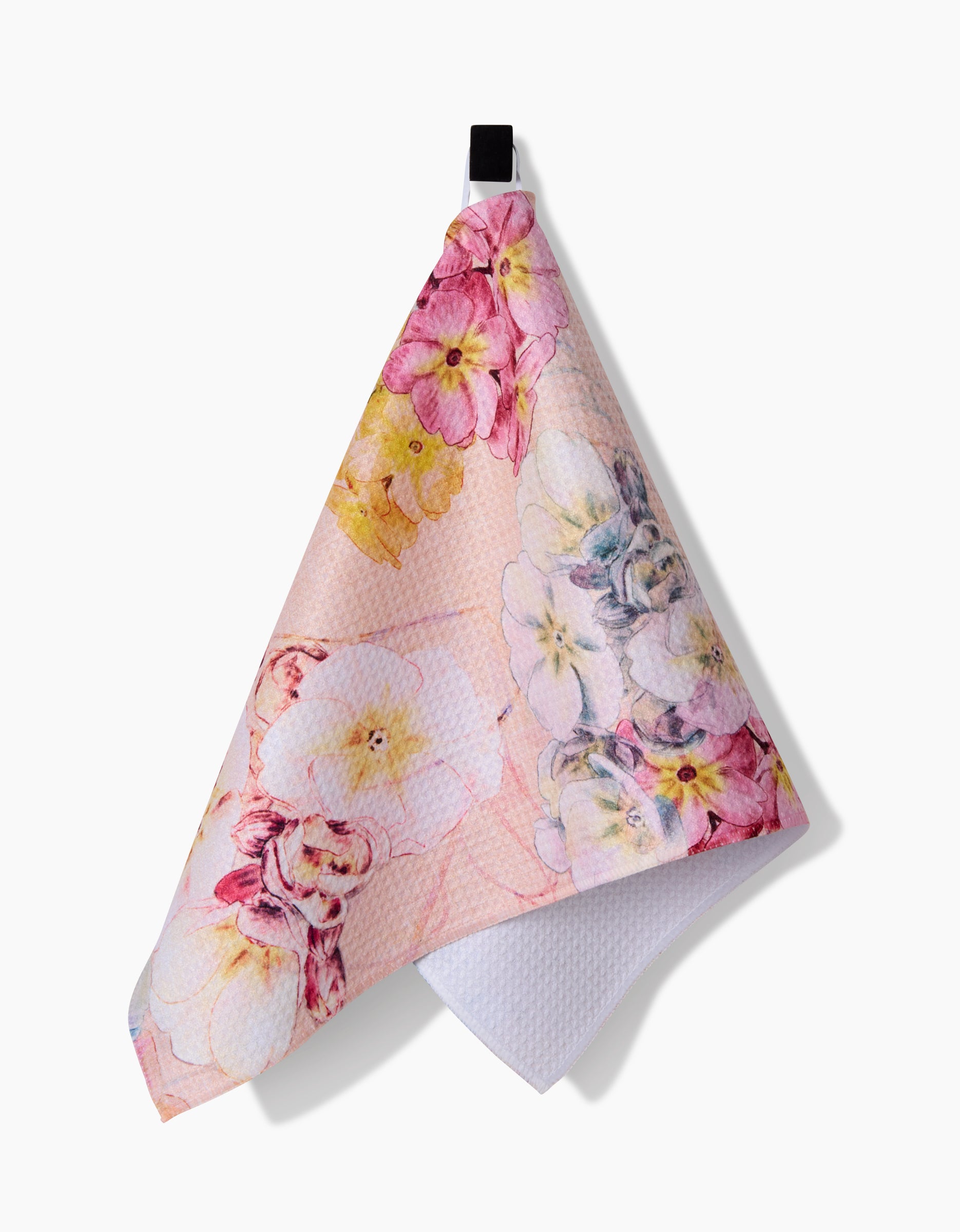 The Pascale Dilger Primroses bar towel, made from recycled materials, features a pastel floral pattern with pink, yellow, and purple flowers and hangs by a black loop against a white background.