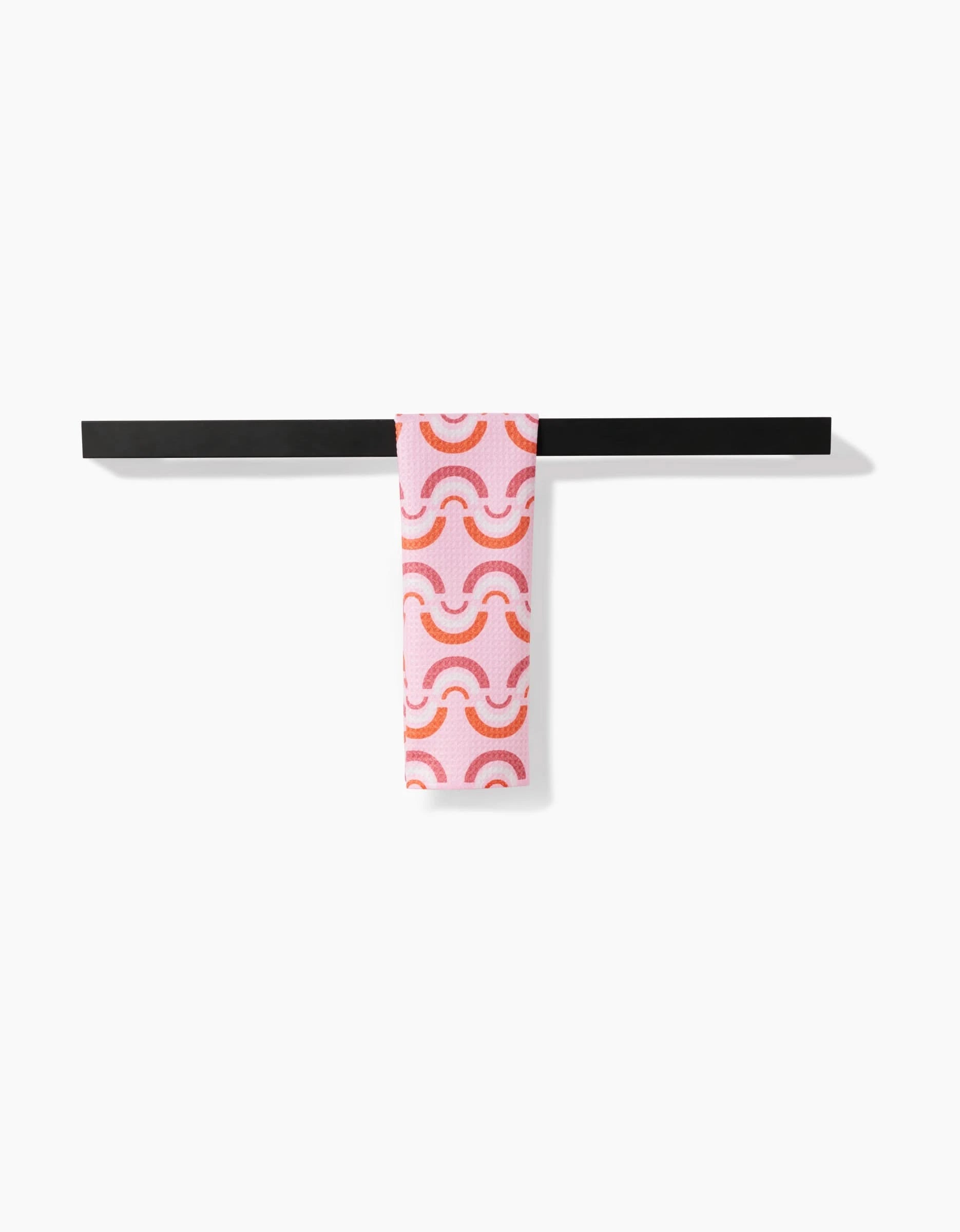 The Rainbow Waves bar towel by Whitney Urquhart, made from recycled materials, features an orange and red wave pattern and hangs neatly on a black bar against a white background.
