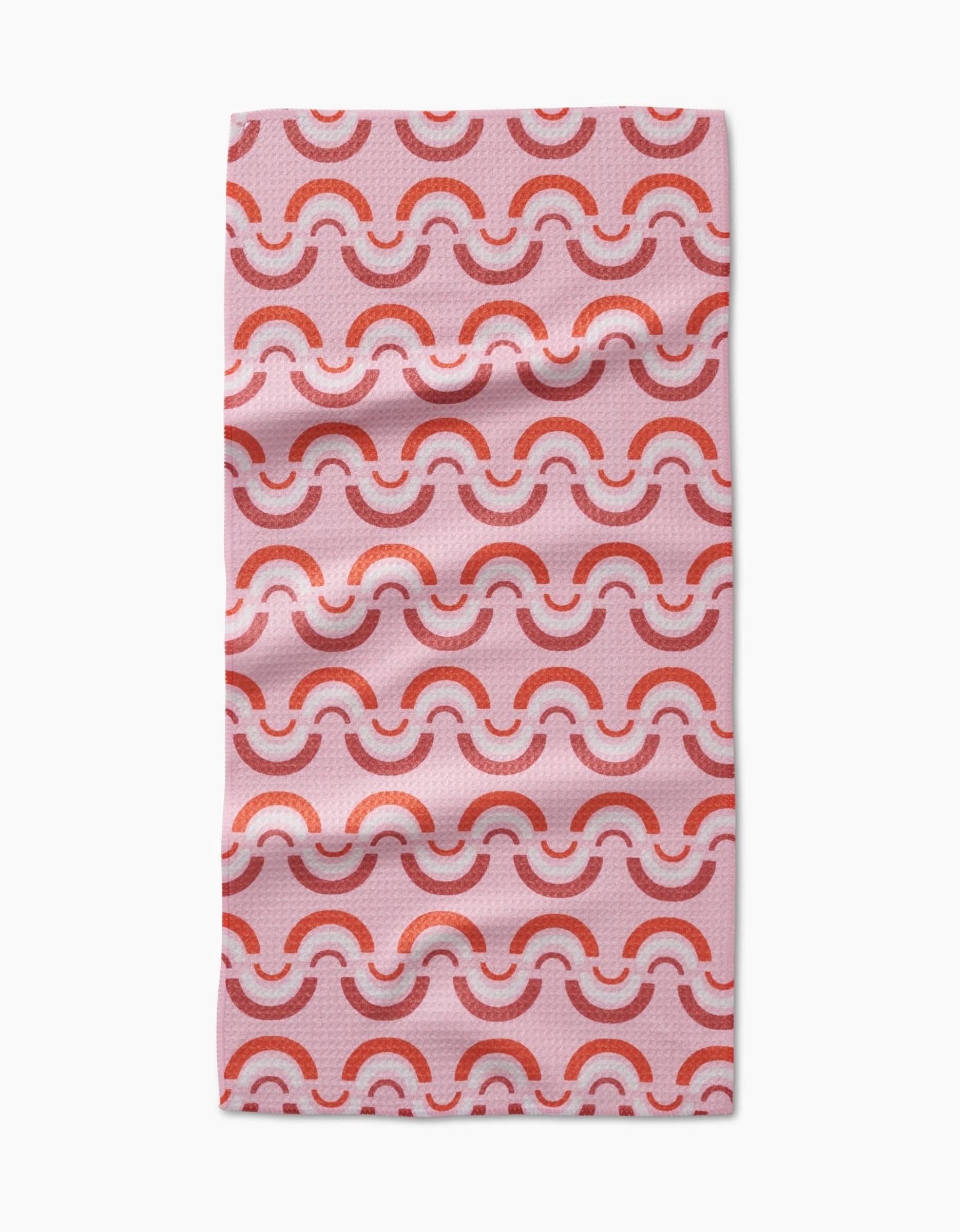 The Rainbow Waves Bar Towel by Whitney Urquhart features a repeating pattern of red and pink semicircles and arches on light pink, made from soft Geoweave™ fabric with slight folds and a gentle texture.