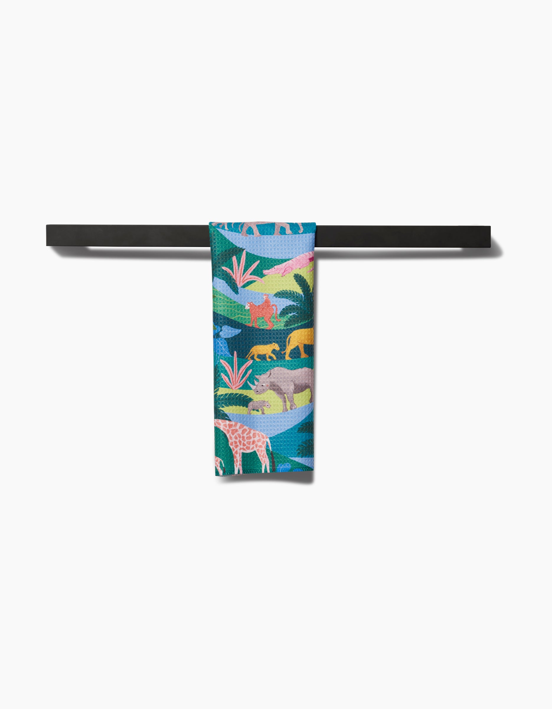 The Rainforest bar towel by Ceyda Alasar, featuring vibrant lions, elephants, and giraffes on recycled fabric, is draped over a sleek black horizontal bar against a white background.