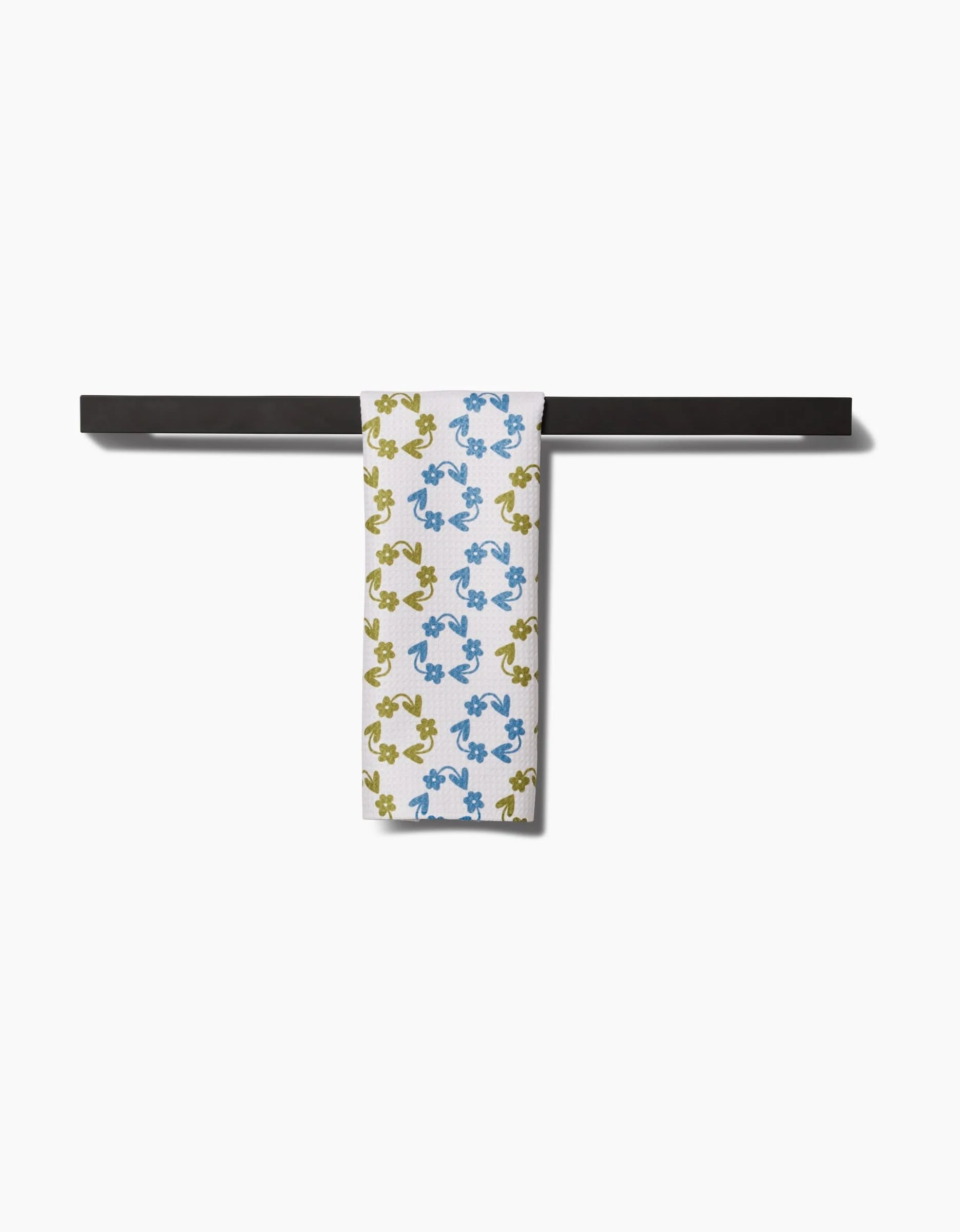 The Kayla Ann Recycled Floral bar towel, featuring blue and yellow abstract floral patterns, hangs over a sleek black bar. Made from ultra-absorbent materials for optimal performance and style against a clean white background.