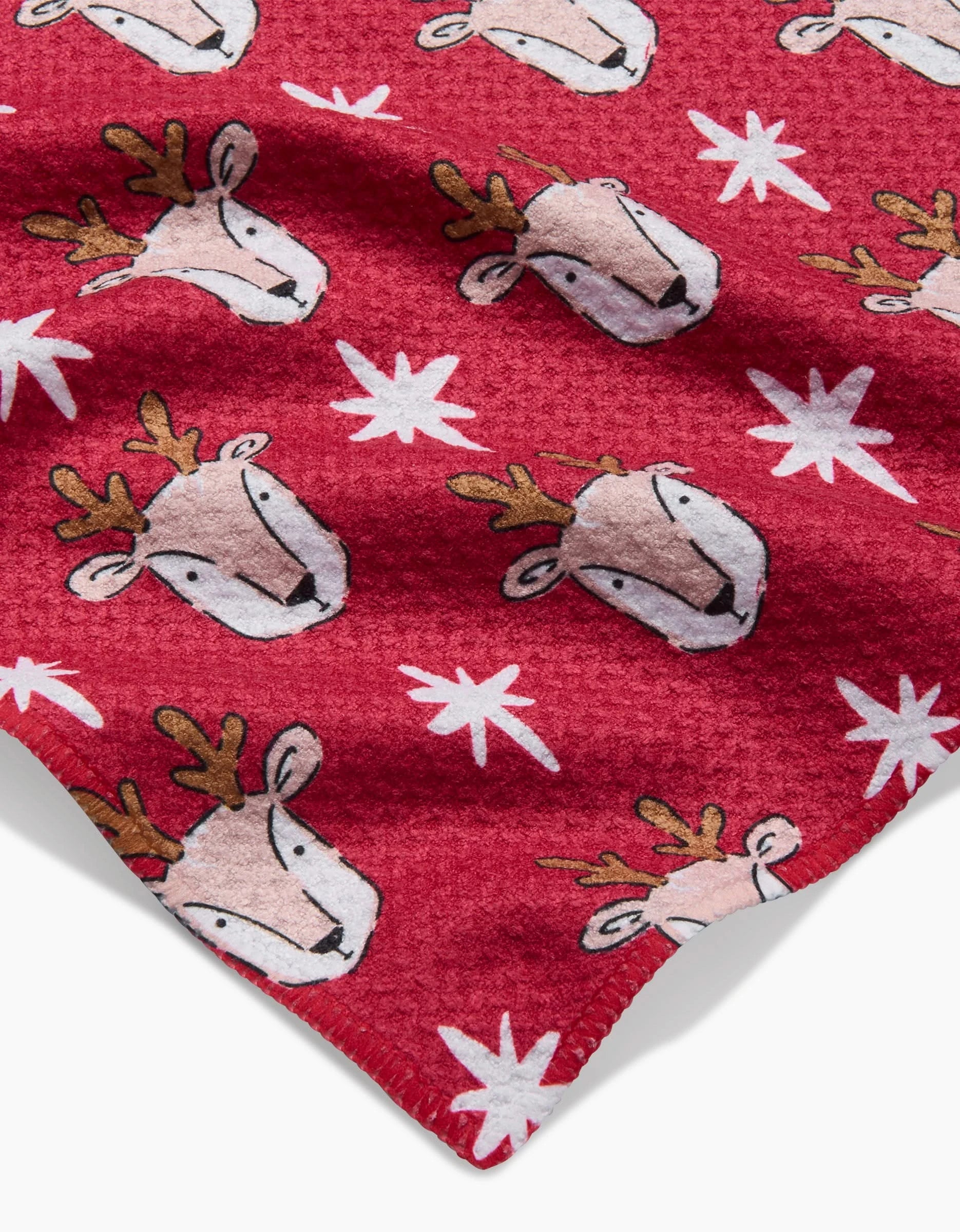 Reindeer Star by Hufton Studio is a red fleece fabric with cartoon reindeer faces and white stars, ideal for crafting a festive, ultra-absorbent kitchen towel to add holiday cheer to your home.