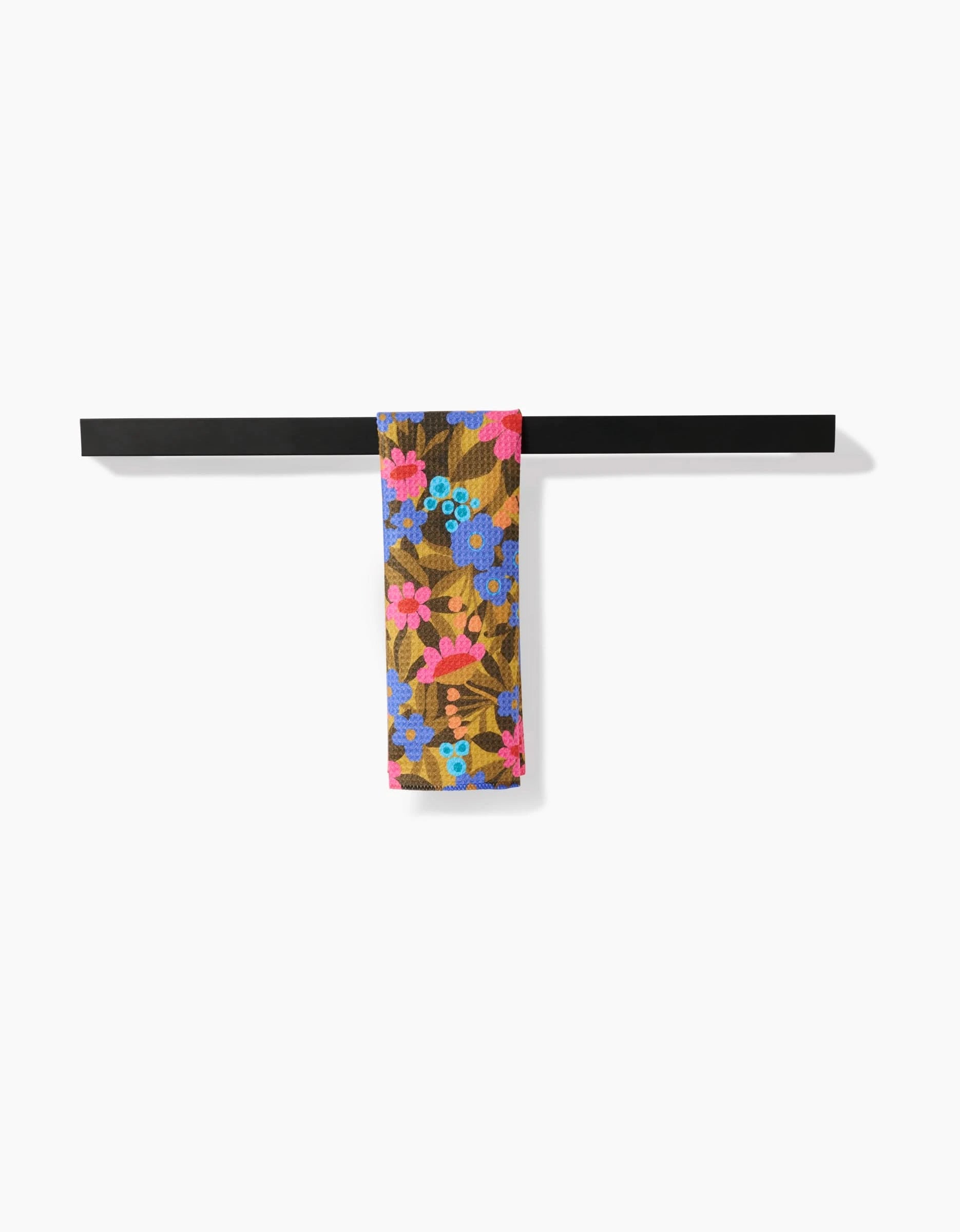 The Lisa Nelson Retro Garden Bar Towel, featuring a colorful floral pattern and made from recycled materials, hangs neatly over a horizontal black metal bar against a plain white background.