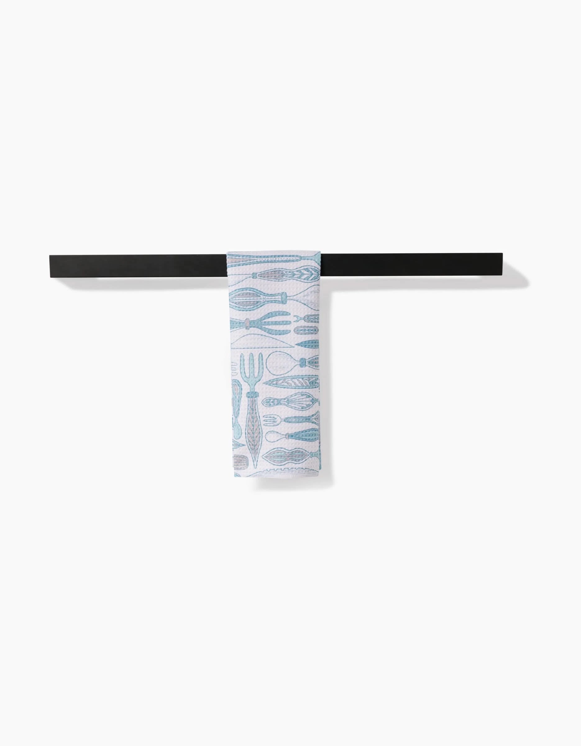 The Romy bar towel by Amy MacCready, made from ultra-absorbent Geoweave fabric and featuring blue utensil patterns, hangs neatly over a simple black bar against a plain white background.