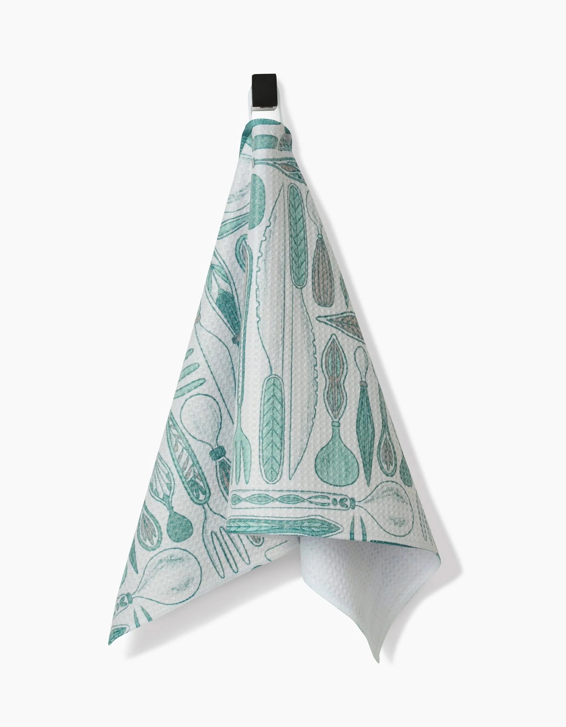 The Romy bar towel by Amy MacCready is white, crafted from ultra-absorbent Geoweave fabric, and displays teal kitchen utensil illustrations. It hangs from a black hook against a plain white background.