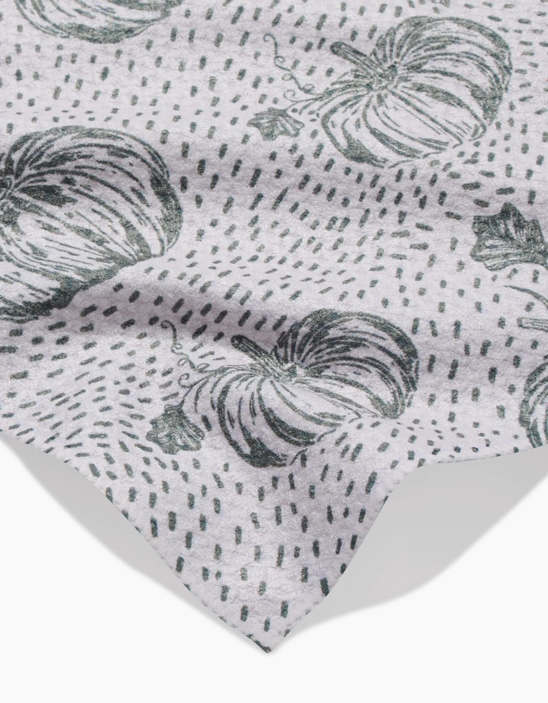 A light gray Sage Pumpkin Field bar towel by Charlie Rowan Designs features a black pumpkin and dotted line pattern. The fabric is slightly wrinkled, with the edge visible in the lower corner.