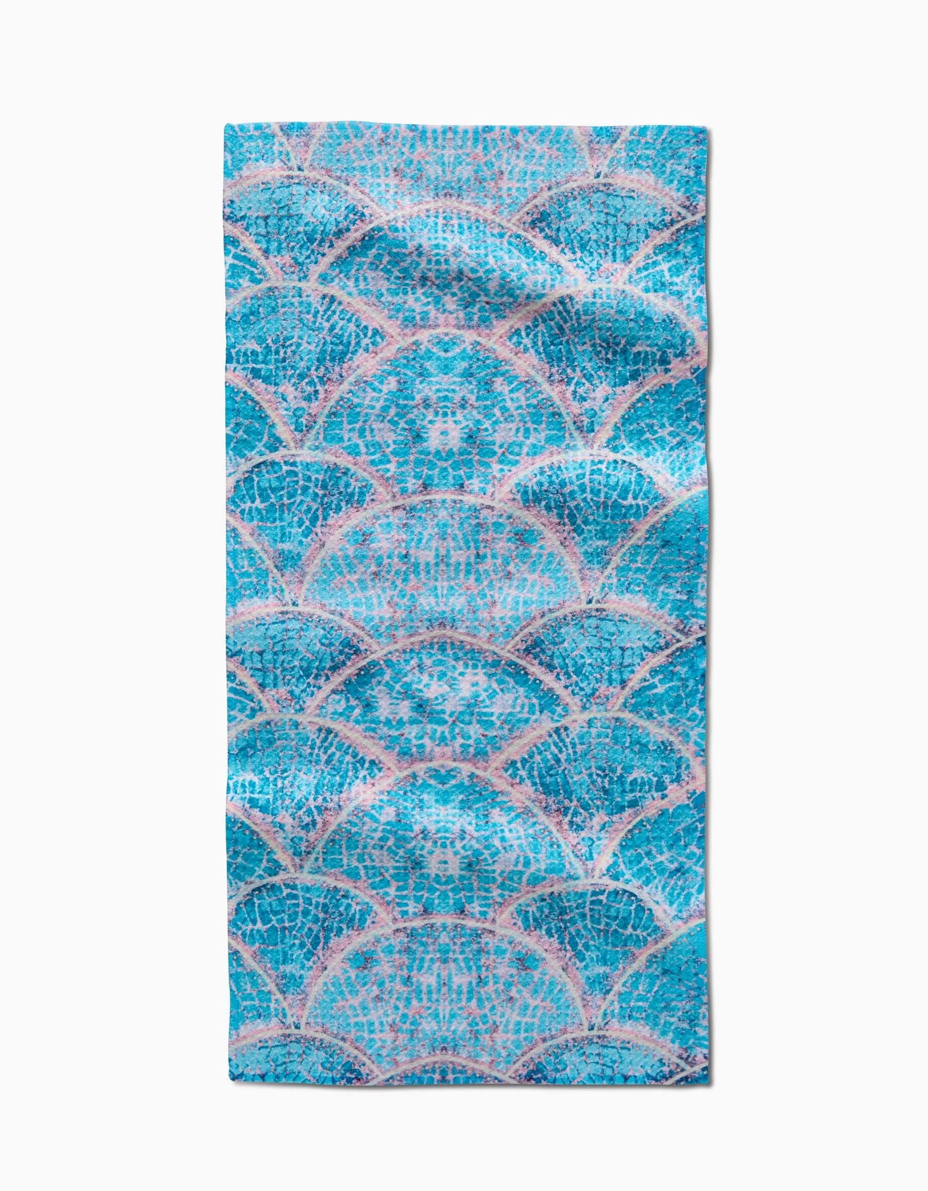 The Scallop Hills bar towel by Taryn Brennan features overlapping blue and teal scales outlined in pink on white, with absorbent Geoweave fabric for effective drying.