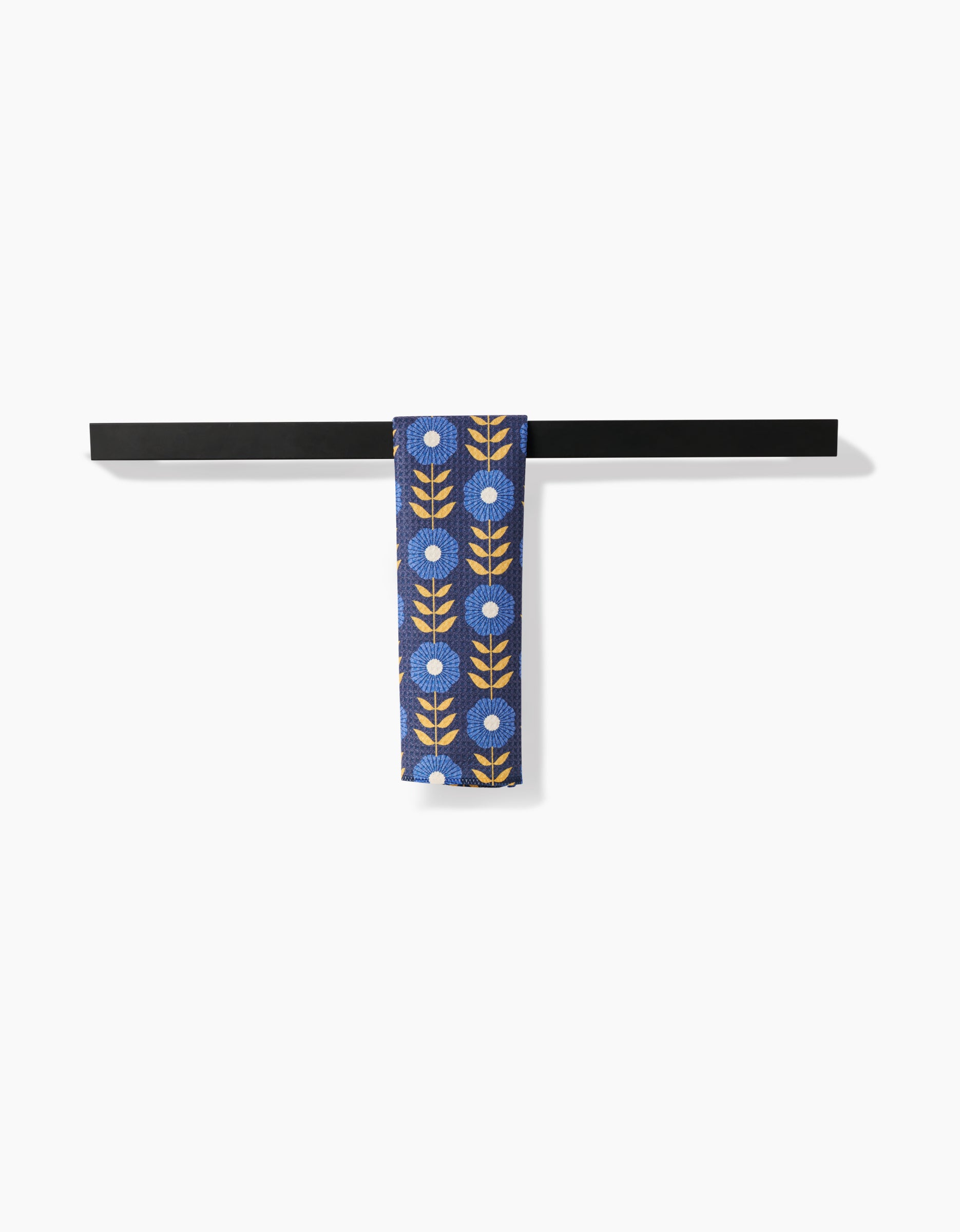 The Scandi Floral necktie by Megan Kampa, crafted from eco-friendly Geoweave fabric, displays white flowers and yellow leaves on blue, hanging over a black bar with a white background.