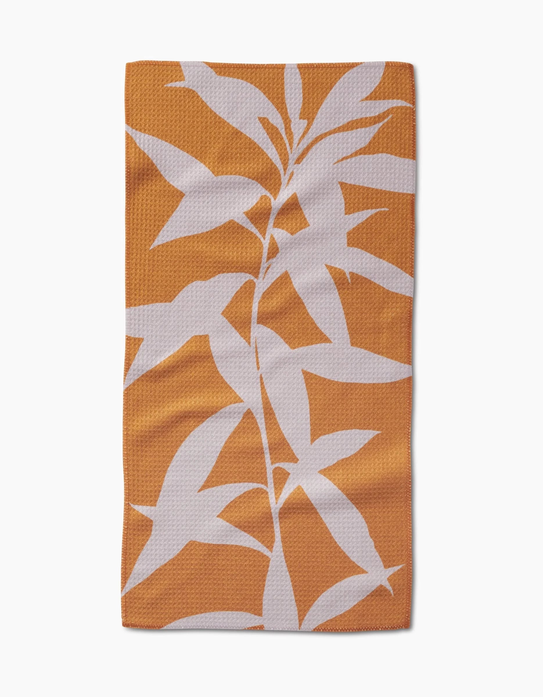 PrintedPlant’s Solidago towel features a modern, simple white leafy plant pattern across an orange rectangular bar surface. Crafted from Geoweave fabric, it offers a bold solid orange background and stylish design.