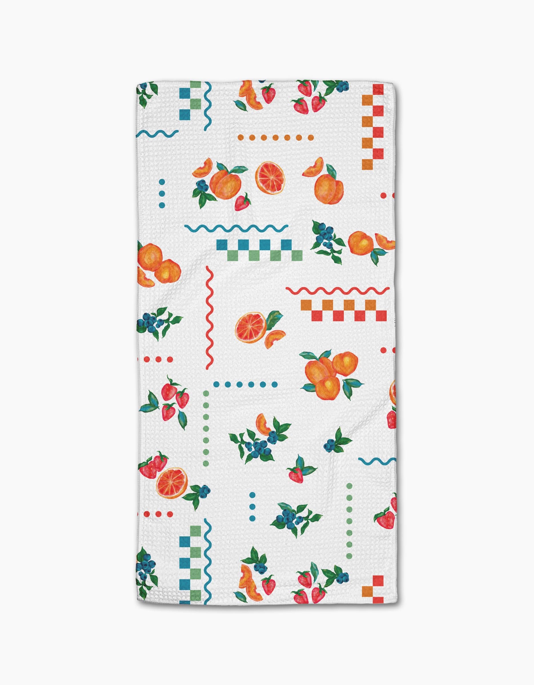 The Aubrey Fairchild Sweet Pickings towel features white Geoweave fabric adorned with colorful oranges, strawberries, blueberries, and red, blue, and green geometric patterns.