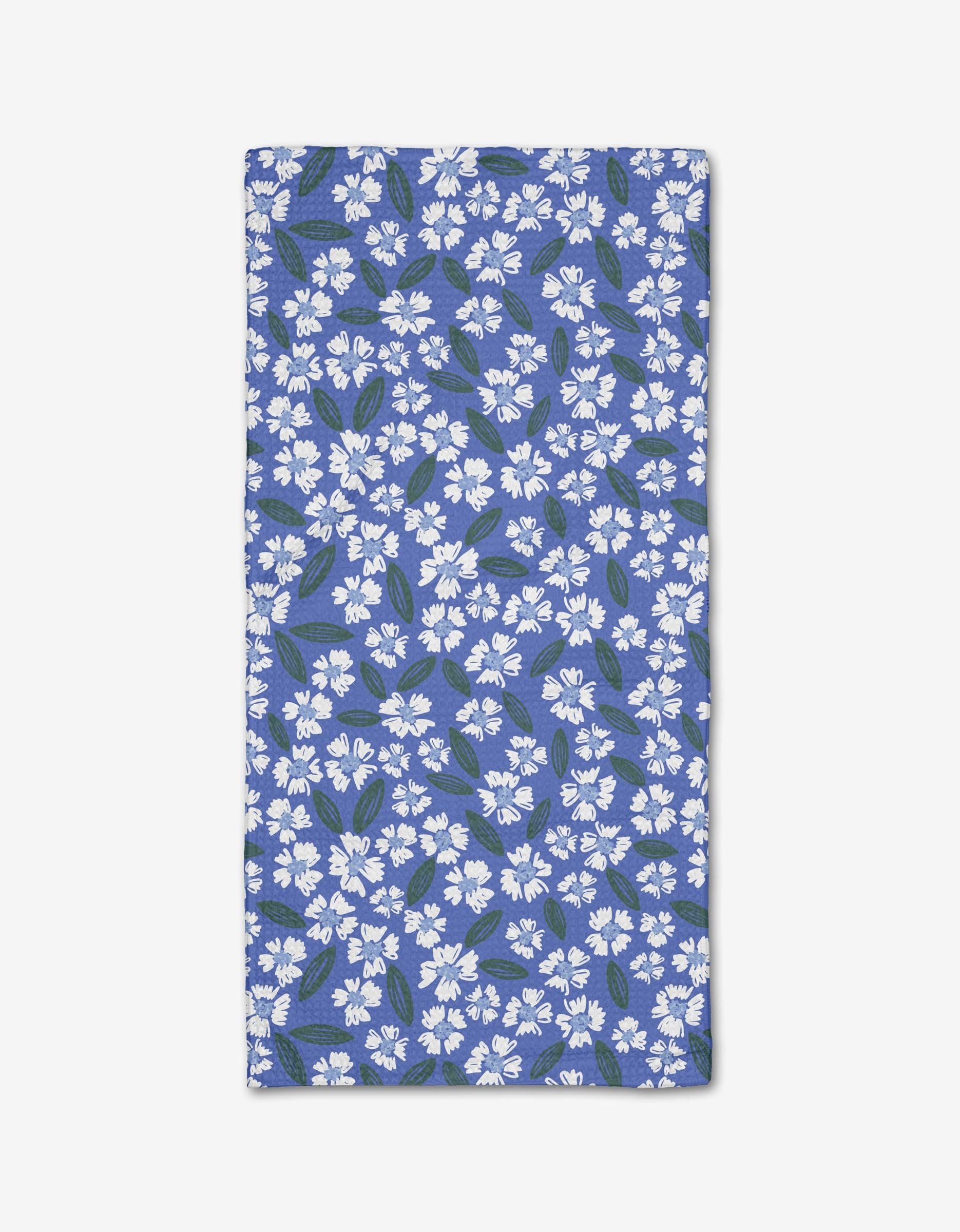 The Hufton Studio Sweetie Floral bar towel, made from eco-friendly Geoweave fabric, features a rectangular blue design with small white flowers and green leaves, shown flat on a white background.