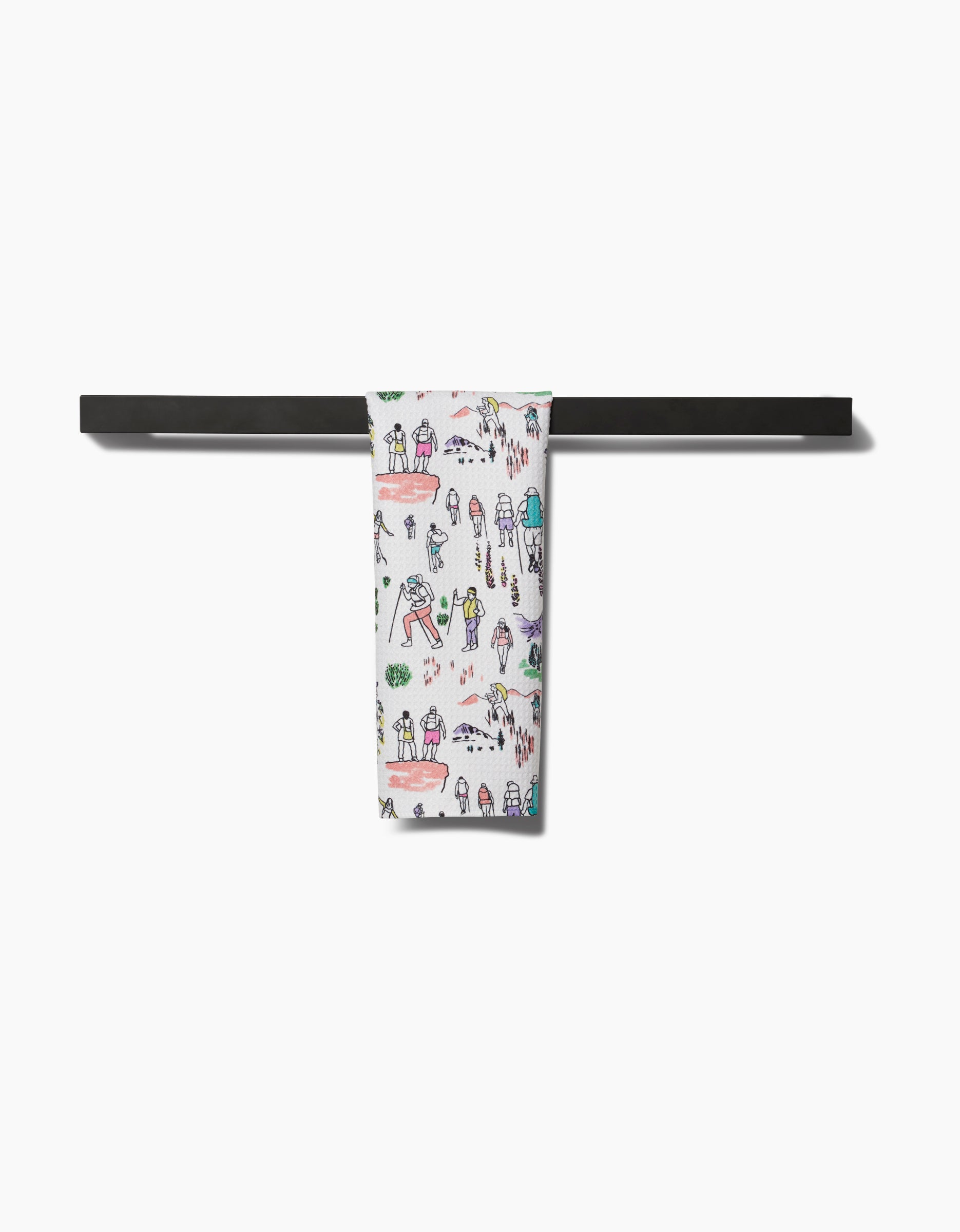The Take A Hike Bar Towel by Elisabeth Wing, featuring playful hand-drawn people and trees on ultra-absorbent Geoweave fabric, hangs neatly on a black towel bar, standing out against the white background.