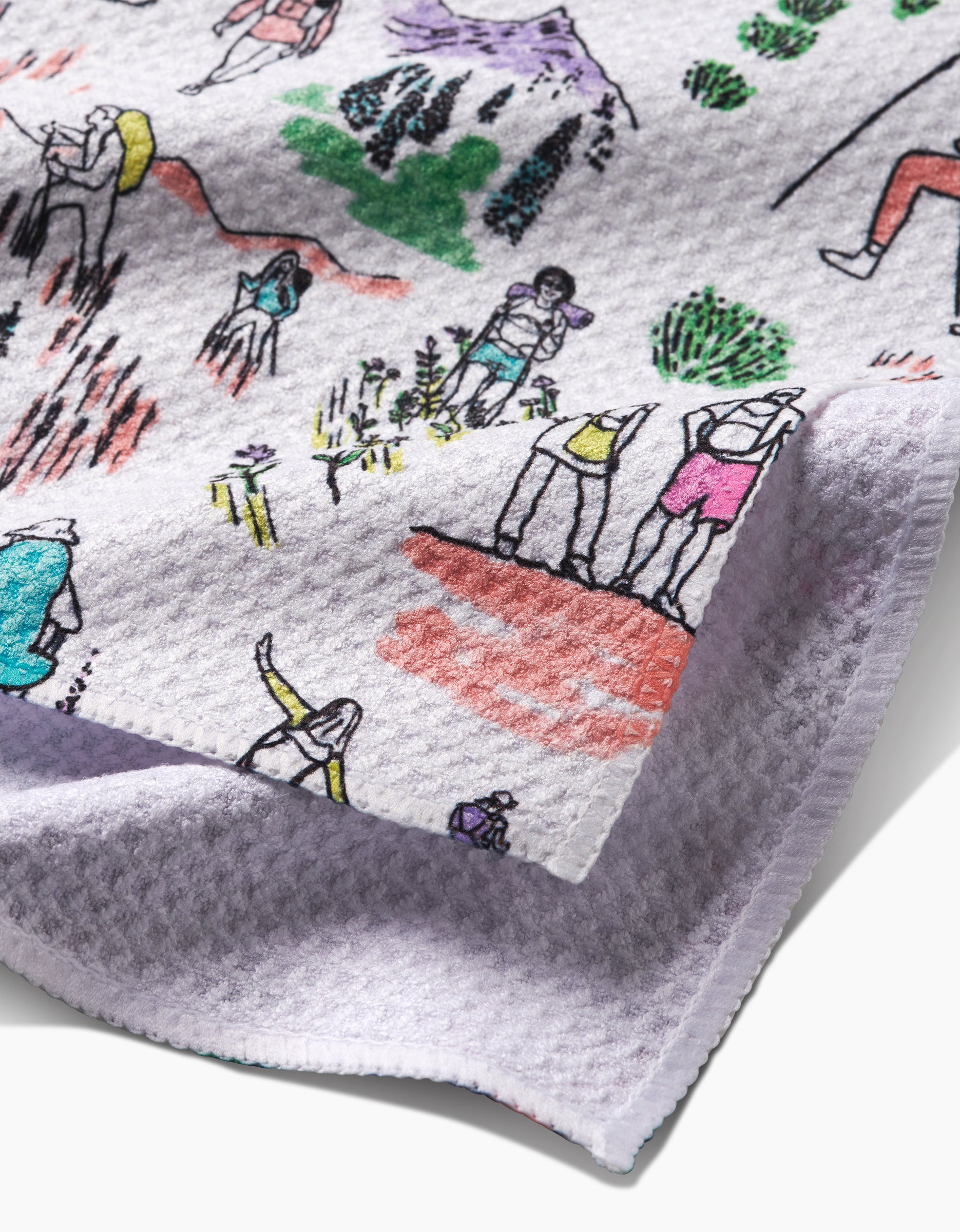 A close-up of the Elisabeth Wing Take A Hike bar towel made from ultra-absorbent Geoweave fabric, featuring colorful illustrations of people hiking, climbing, and exploring nature. One corner of the white towel is slightly folded.
