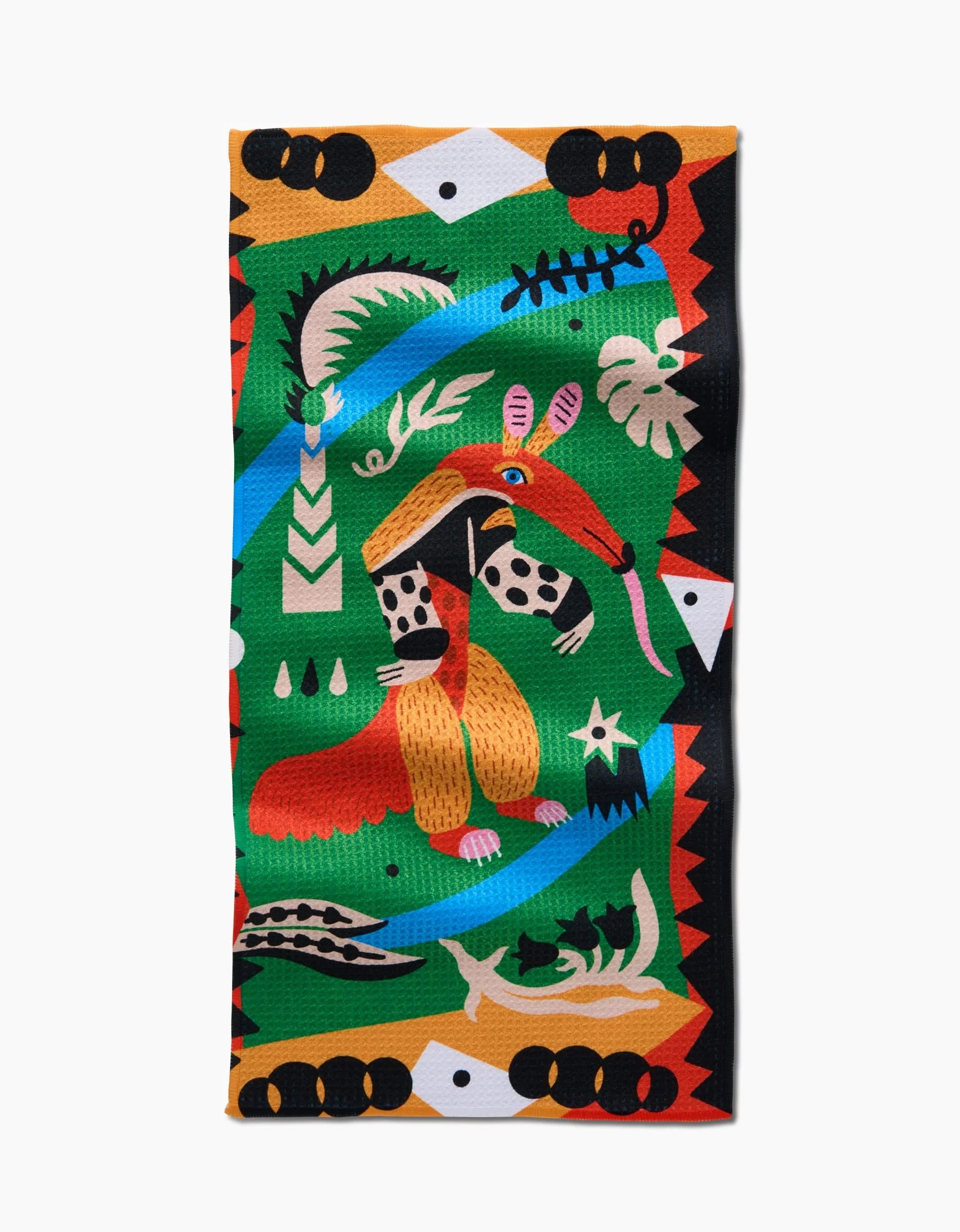 The Tamanduá Bandeira Bar Towel by Camila Leão features a stylized anteater with abstract shapes, plants, and a fish skeleton in green, red, yellow, black, and blue Geoweave fabric.