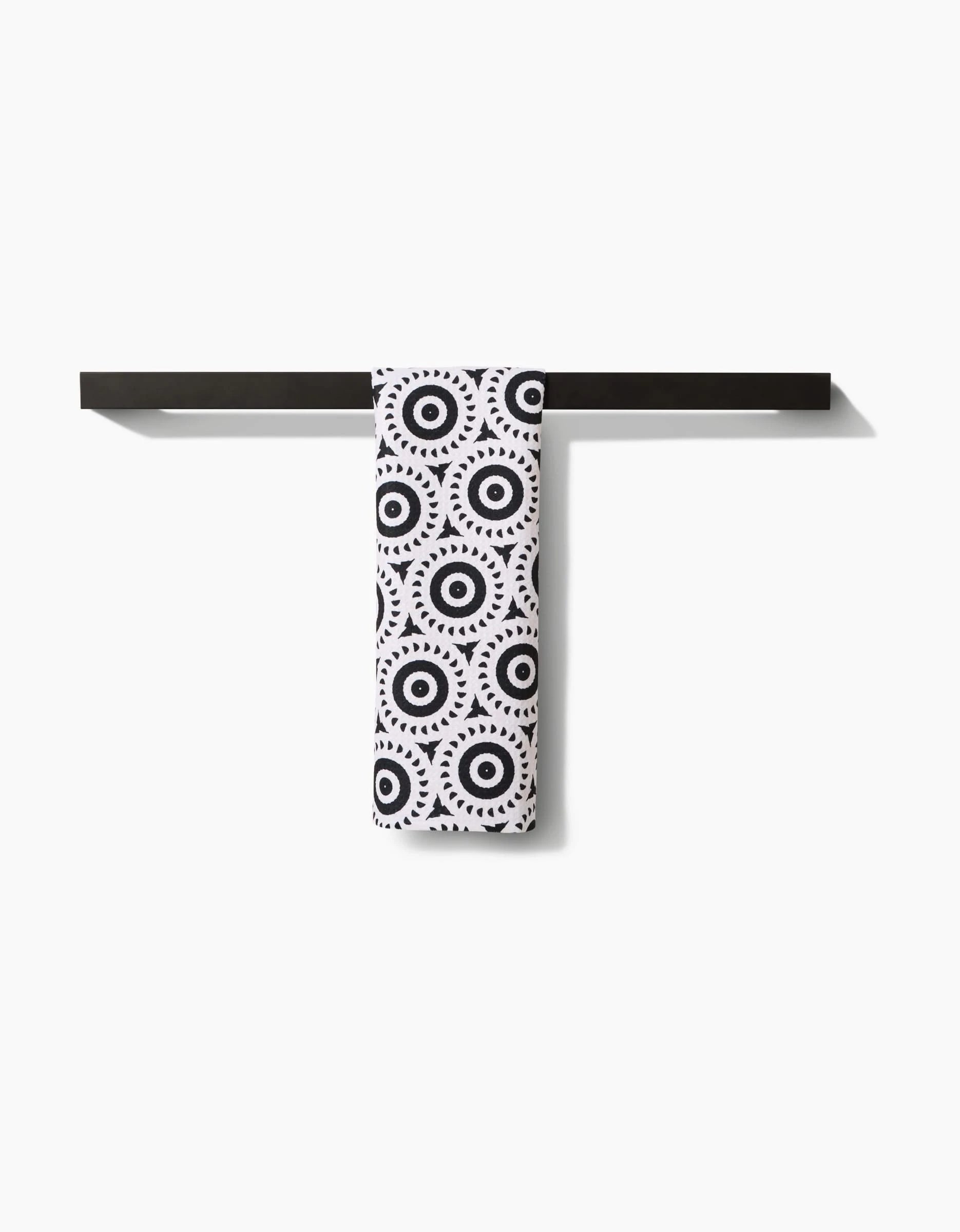 A black Bar Towel rack displays Katherine Berkeleys Texas Two Step—a white towel featuring black concentric circles and dots, made from premium Geoweave fabric. The background is plain white.