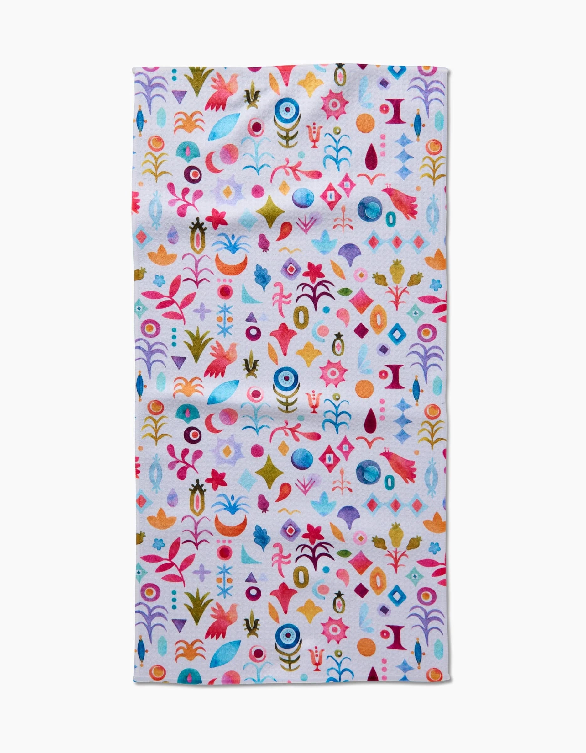 The Tula rectangular bar towel by Maayan Alper-Swan is made from recycled materials and features a vibrant, whimsical pattern of abstract florals, leaves, and geometric shapes in pink, blue, orange, red, and green on white.