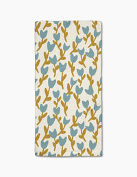 Tulip Garden by Lizzie Clark is a folded white cloth napkin with a blue tulip floral pattern and brown stems, made from recycled materials for an eco-friendly touch.
