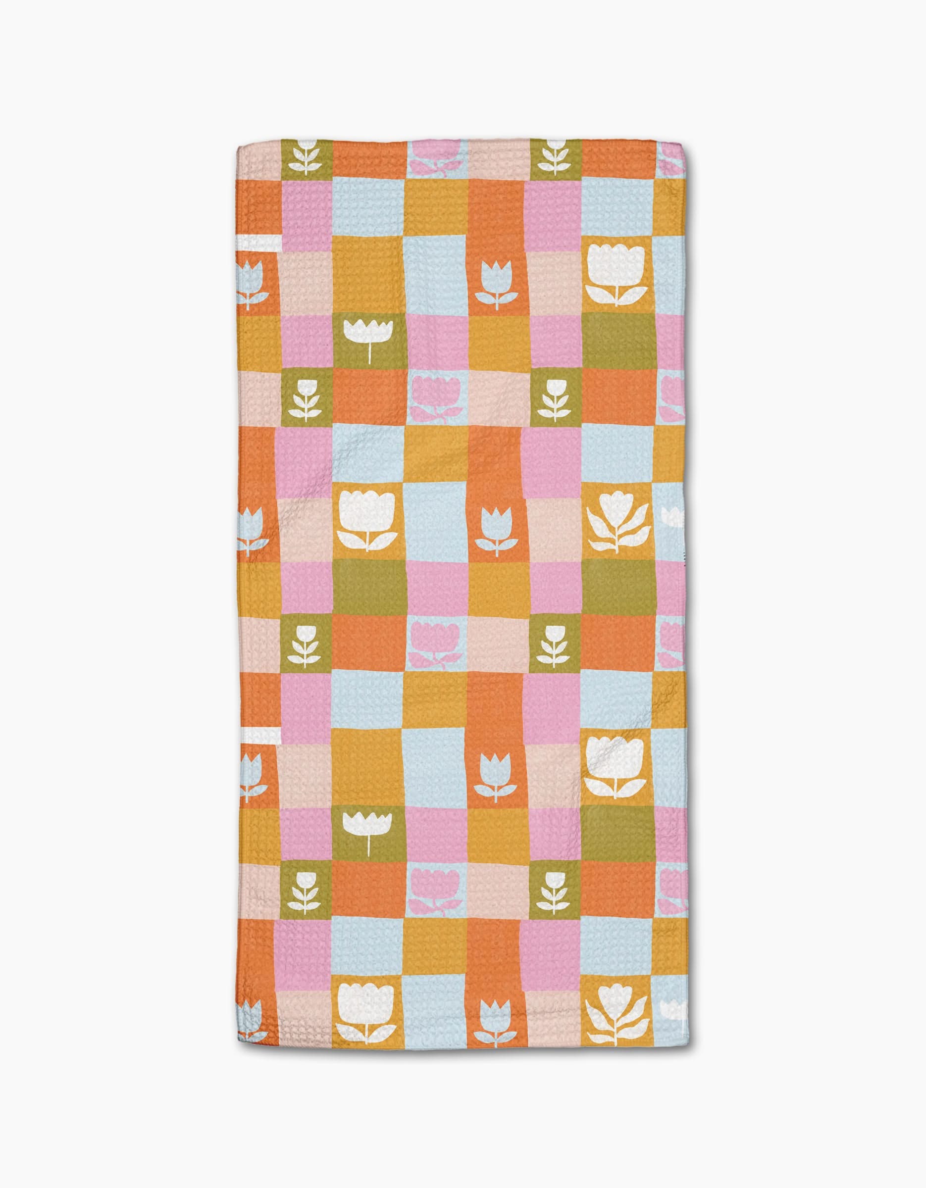 The Tulip Picnic by Lisa Nelson is a rectangular quilted blanket with orange, pink, blue, and green checkered squares, featuring white tulip and leaf motifs—crafted from post-consumer recycled materials for eco-friendly style.