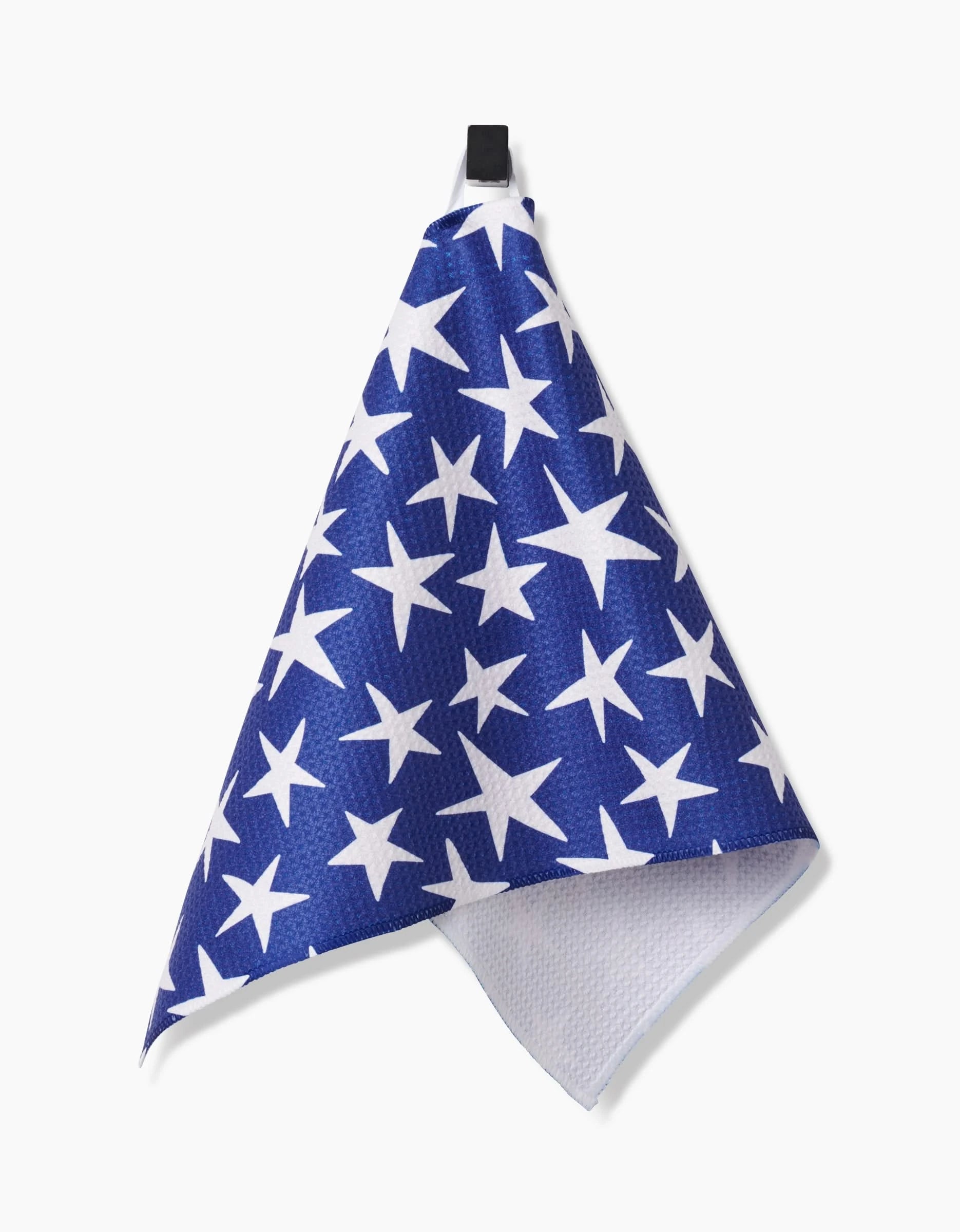 The Mindfulnice USA Stars Bar Towel, featuring large white stars on blue Geoweave fabric, hangs from a black hook against a plain white background.