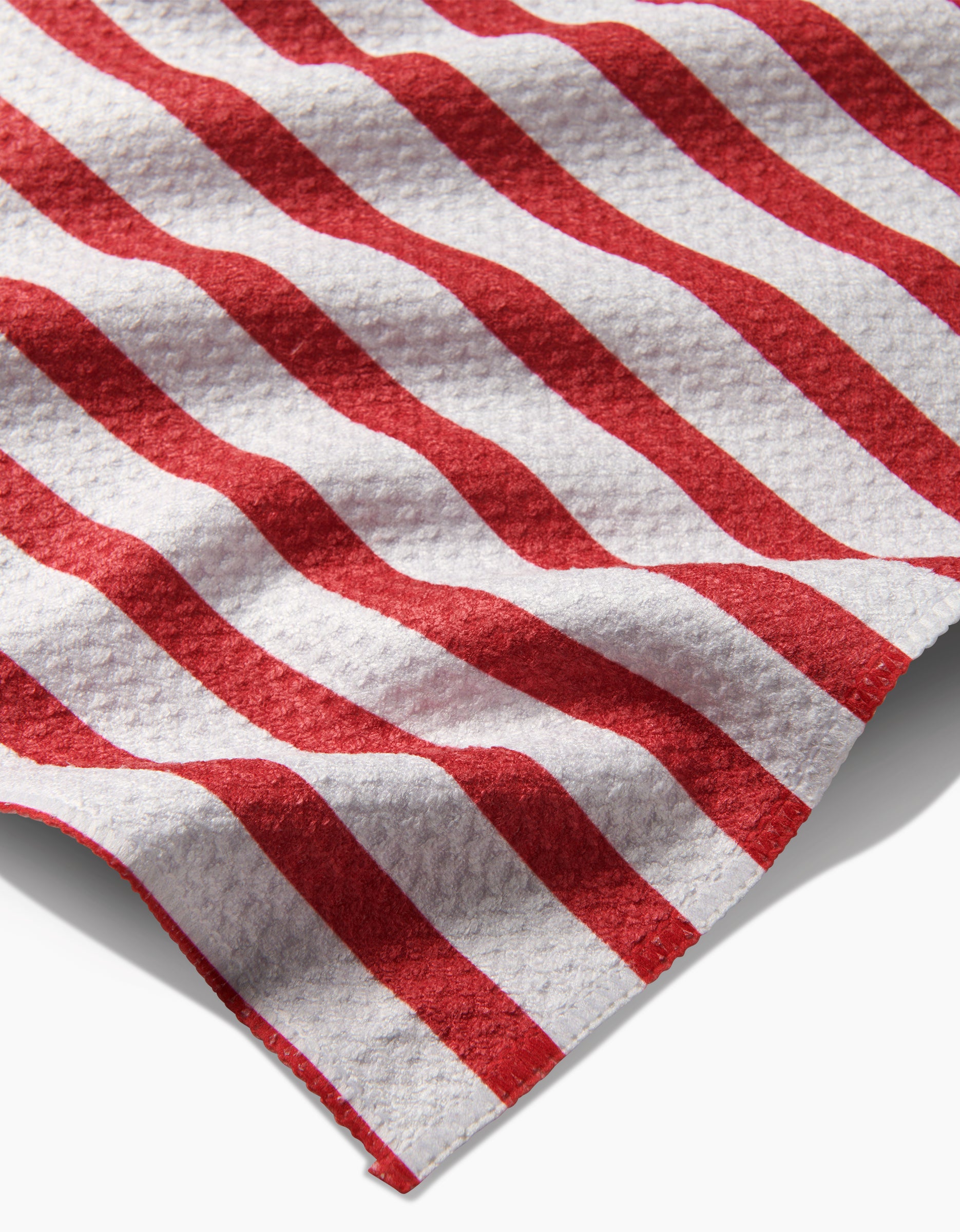 A detailed view of Mindfulnice’s USA Stripes towel, featuring red and white diagonal Geoweave fabric, draped in soft folds against a white background.