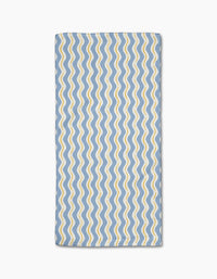 The Wave Ripple Stripes bar towel by Hufton Studio features a rectangular blue Geoweave fabric with wavy yellow and white parallel lines in a repeating pattern, neatly folded and displayed on a white background.
