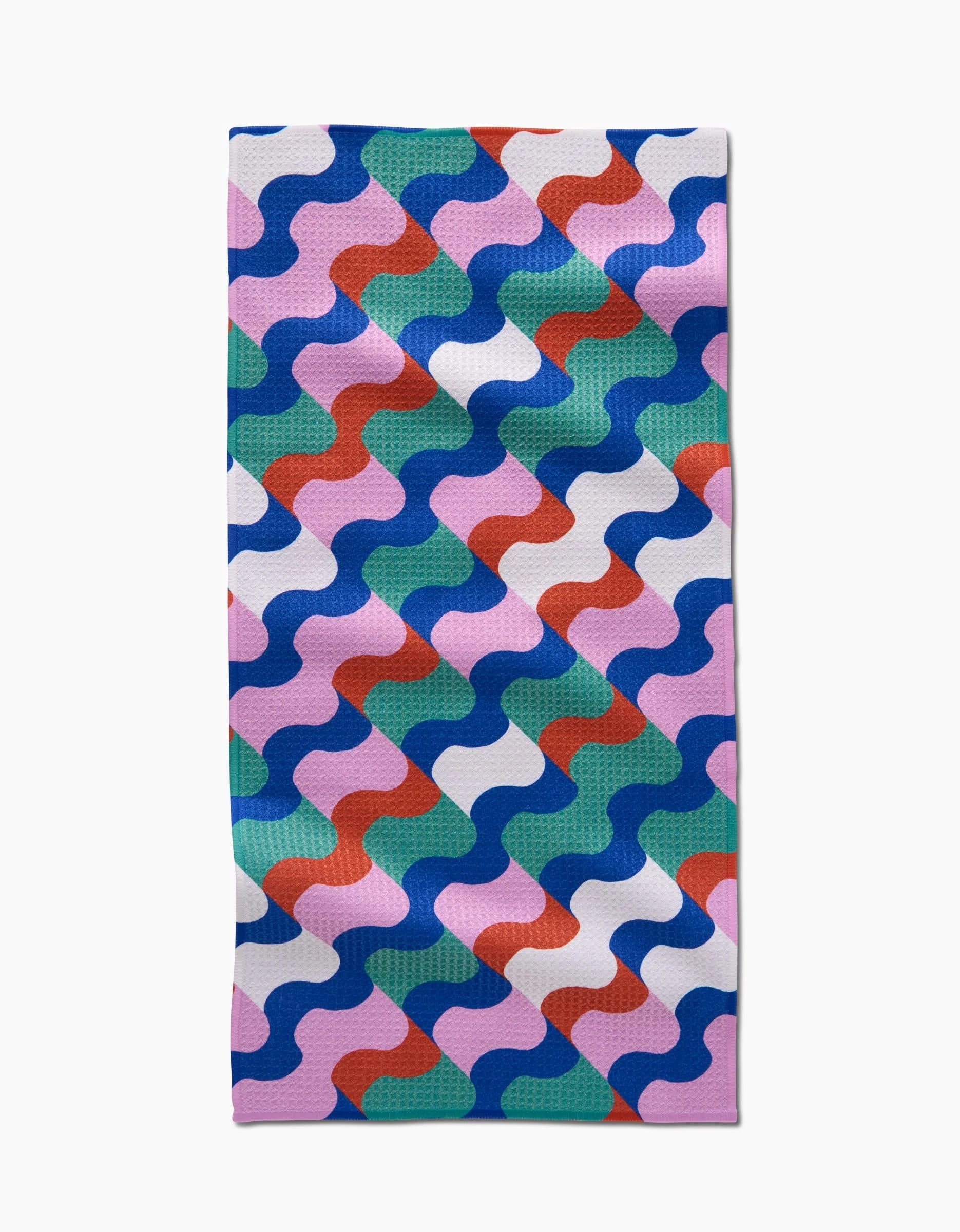The Wavy Stripes bar towel by Claire Iglesias features colorful blue, pink, green, red, and white wavy shapes in diagonal rows on a plain white background and is made from Geoweave fabric.