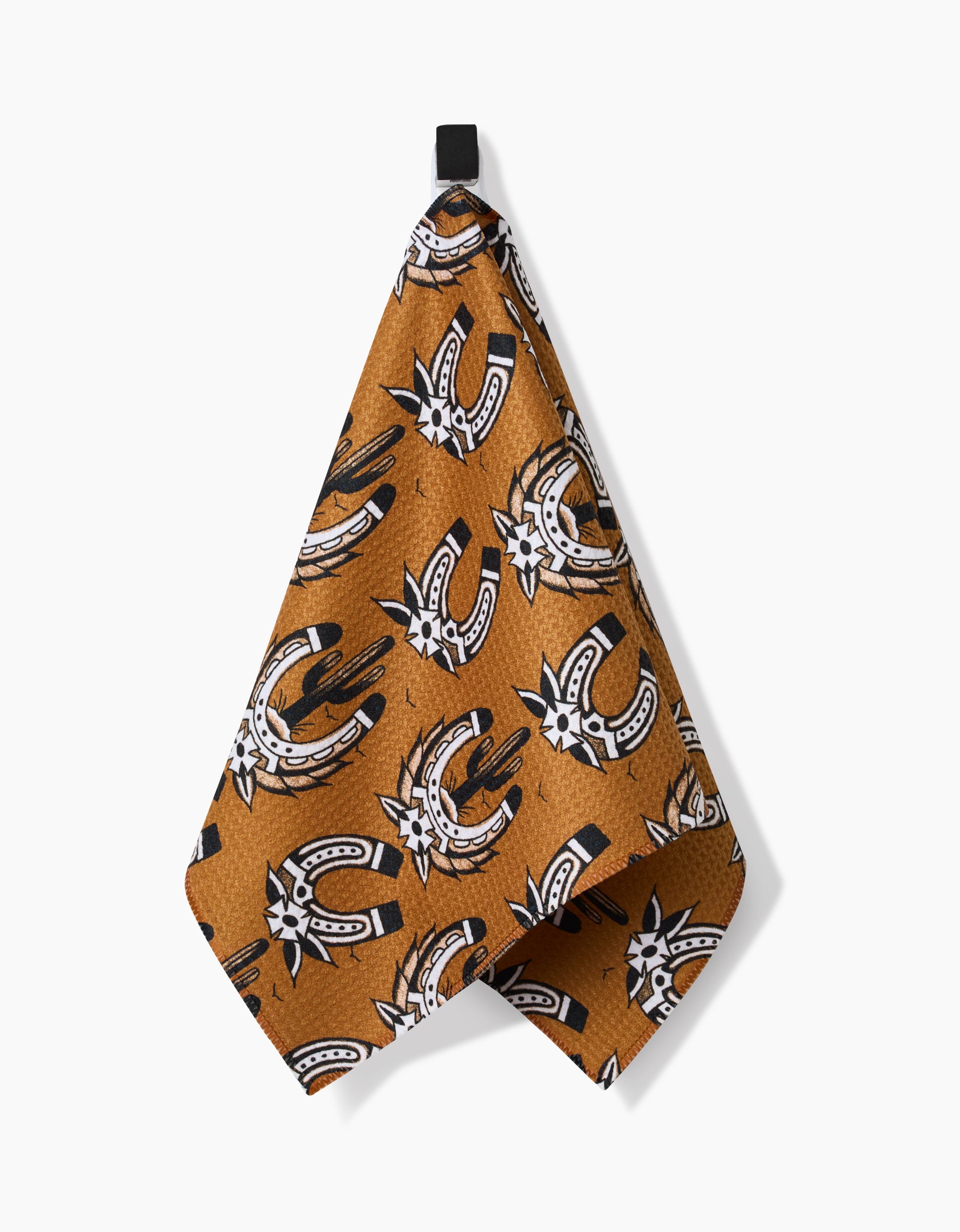 The Cole Strem Western Horseshoes bar towel, made from recycled materials, features a brown background with black, white, and tan horseshoe and spur patterns. It hangs by a black loop against a white backdrop.