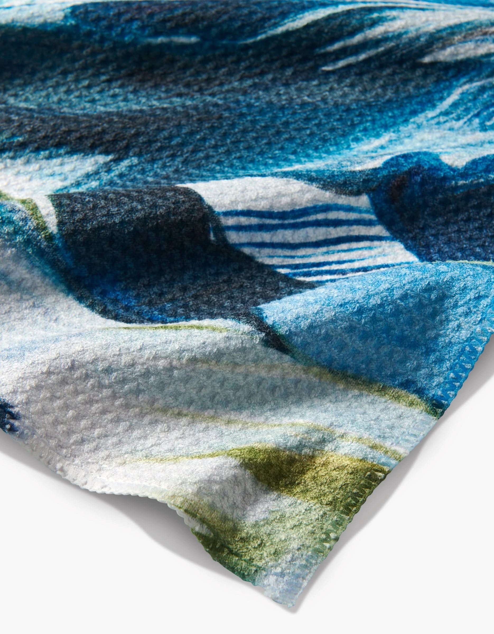A close-up of Kelly Peters’ Where He Laid To Go shows its soft, textured Geoweave fabric with a blue, green, and white abstract pattern and stitched edge against a white background.