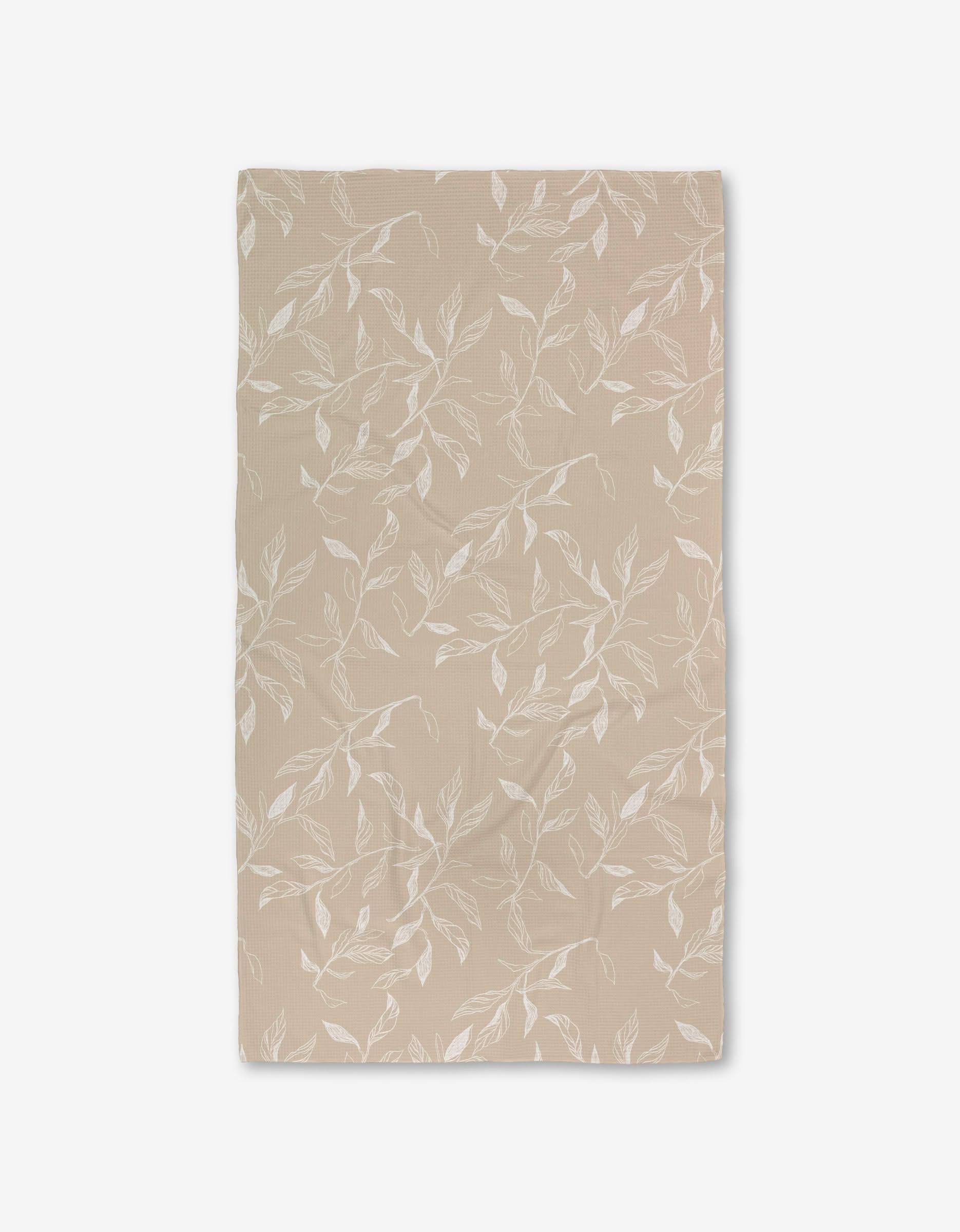 Aubrey Fairchilds Flowing Floral Luxe Bath Towel, beige and rectangular with a white leafy branch pattern and Geoweave technology, is laid flat on a white background.
