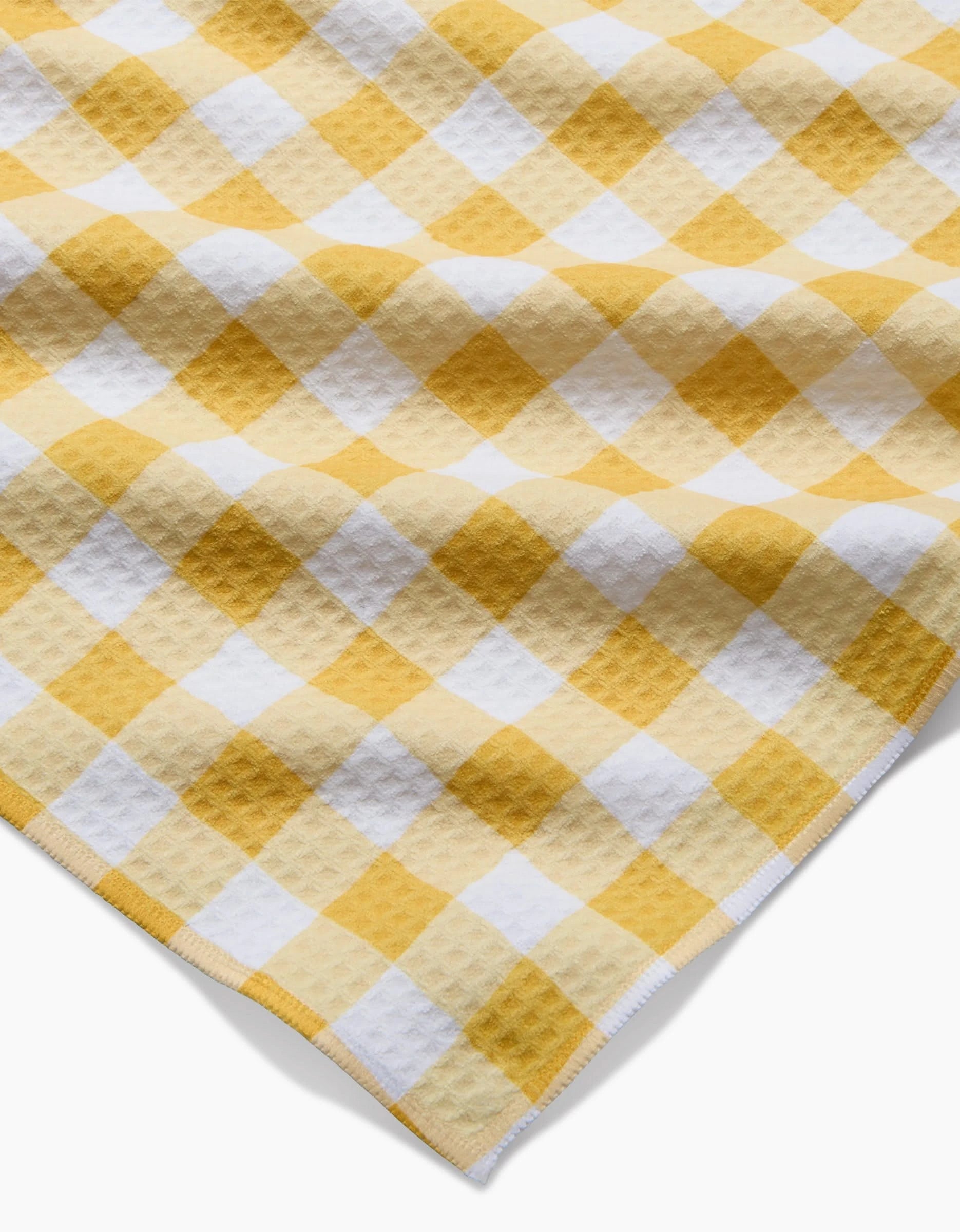 A close-up of Danelys Sidron’s Golden Plaid shows its yellow and white checkered Geoweave fabric with a waffle texture, displayed at an angle with detailed edge stitching.