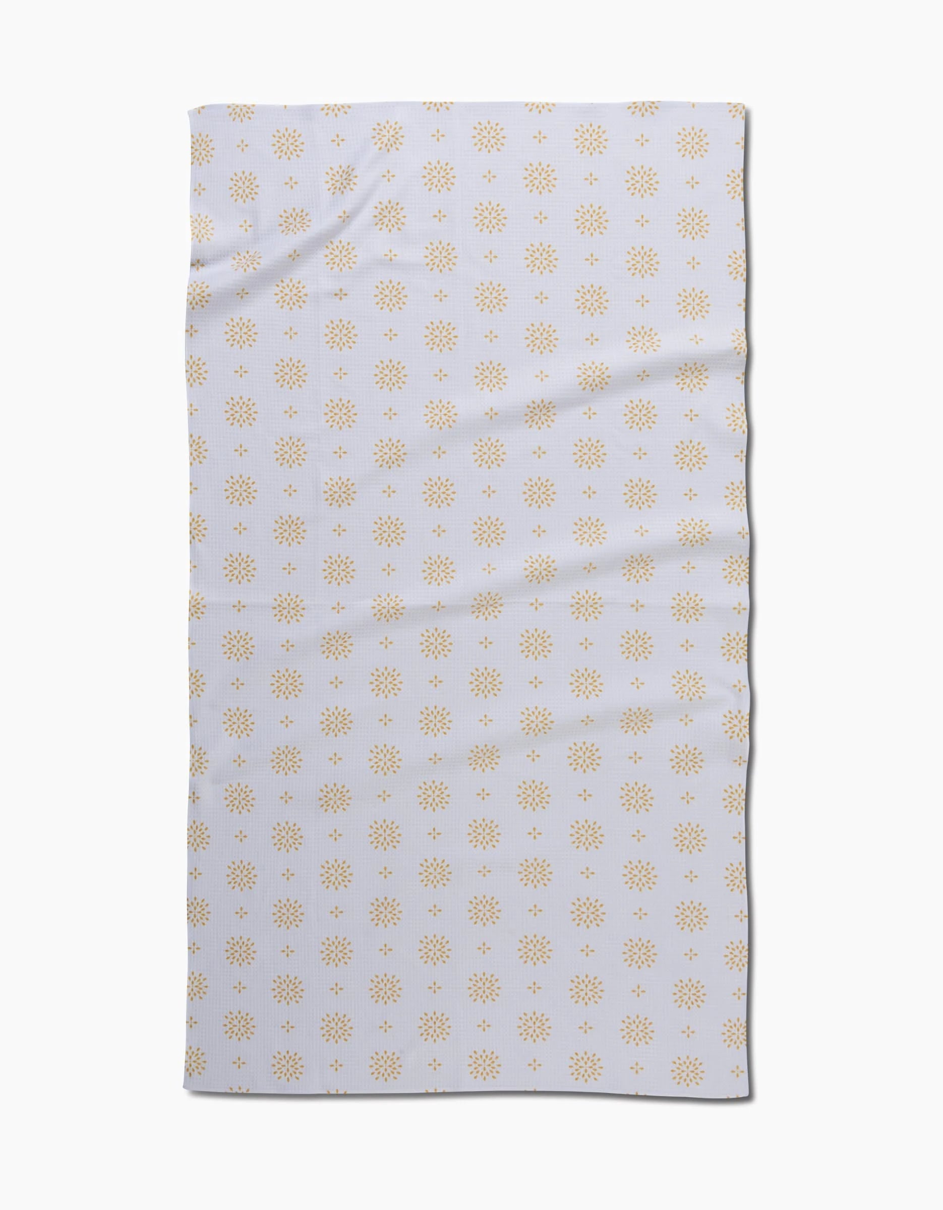 The Danelys Sidron Morning Petals bath towel is rectangular and white, featuring a repeating pattern of small yellow sunbursts. Slightly wrinkled, the towel is displayed on a plain white background.