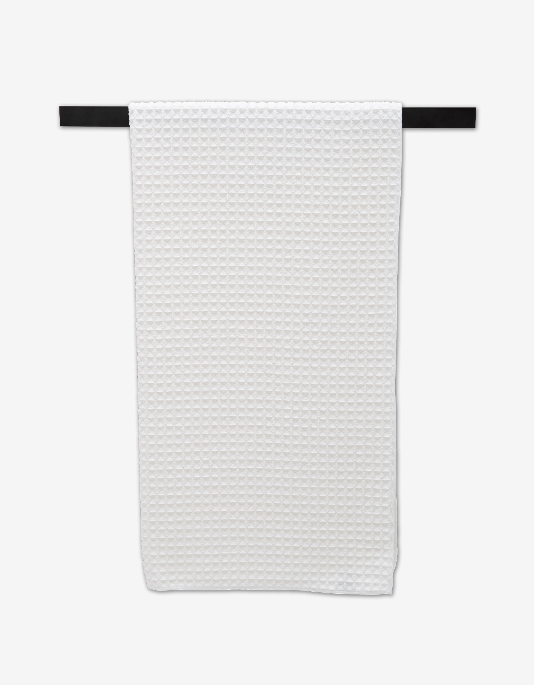 The GEOMETRY Cloud Bath Towel, featuring a white textured waffle pattern, hangs neatly on a horizontal black towel bar against a plain white background.