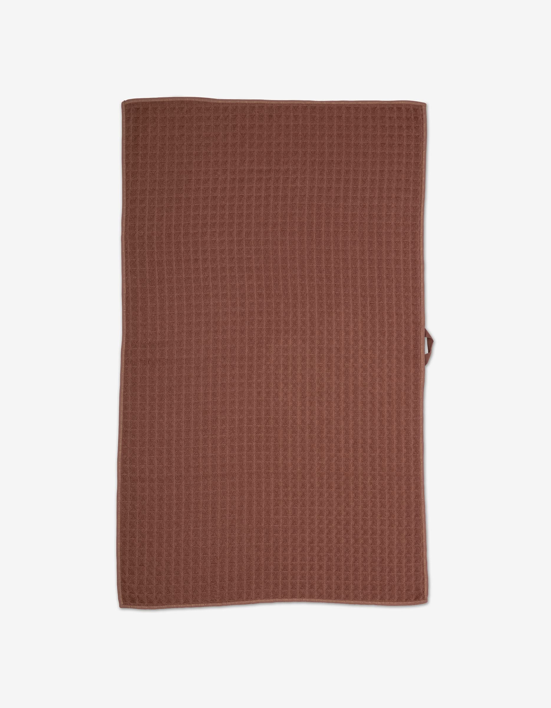 A rectangular, dusty rose GEOMETRY Waffle Bath Towel with a textured surface is laid flat against a white background, highlighting its ultra-absorbent quality and luxurious feel.
