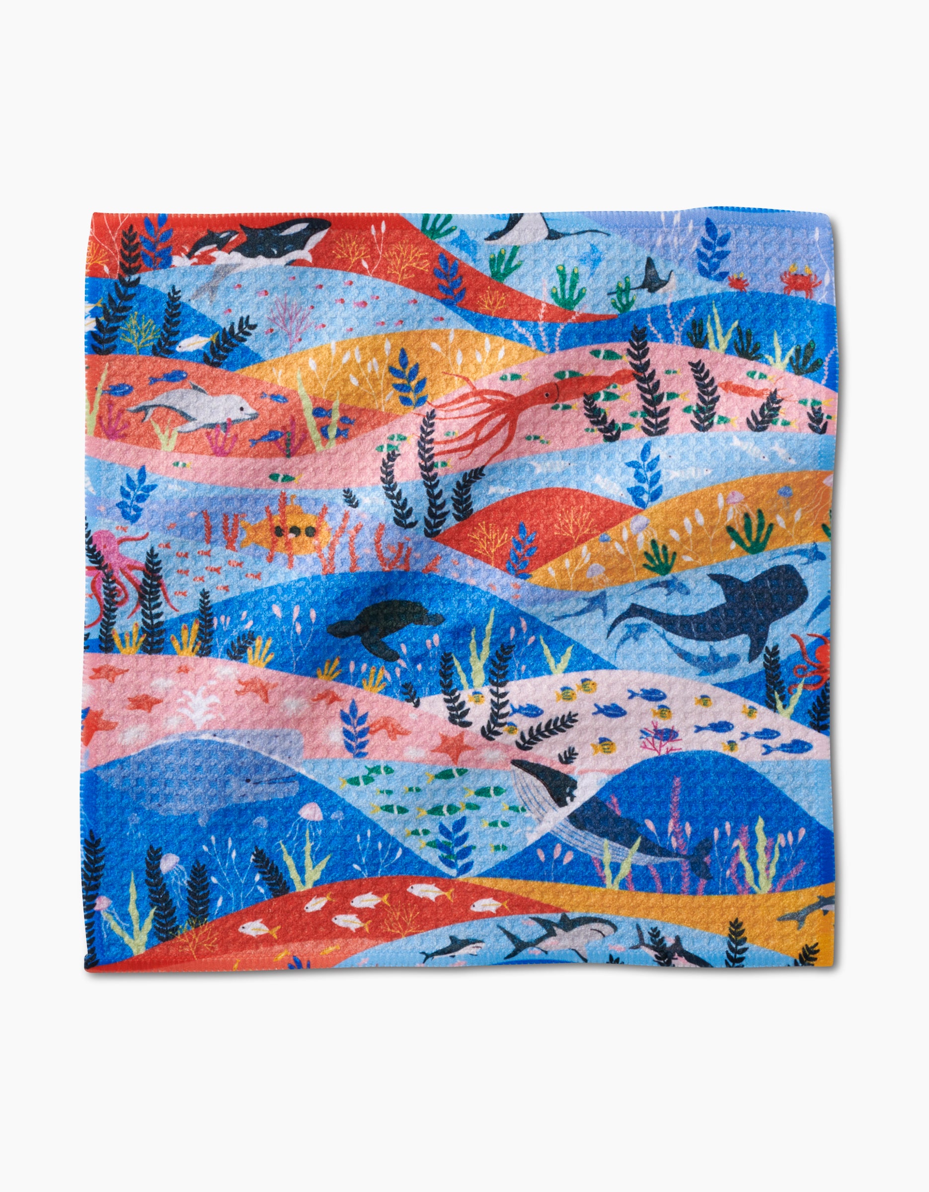 The Oceans dishcloth by Ceyda Alasar is made from recycled materials and features red, orange, pink, and blue waves with whales, sharks, fish, seaweed, and more for a vibrant marine-inspired design.