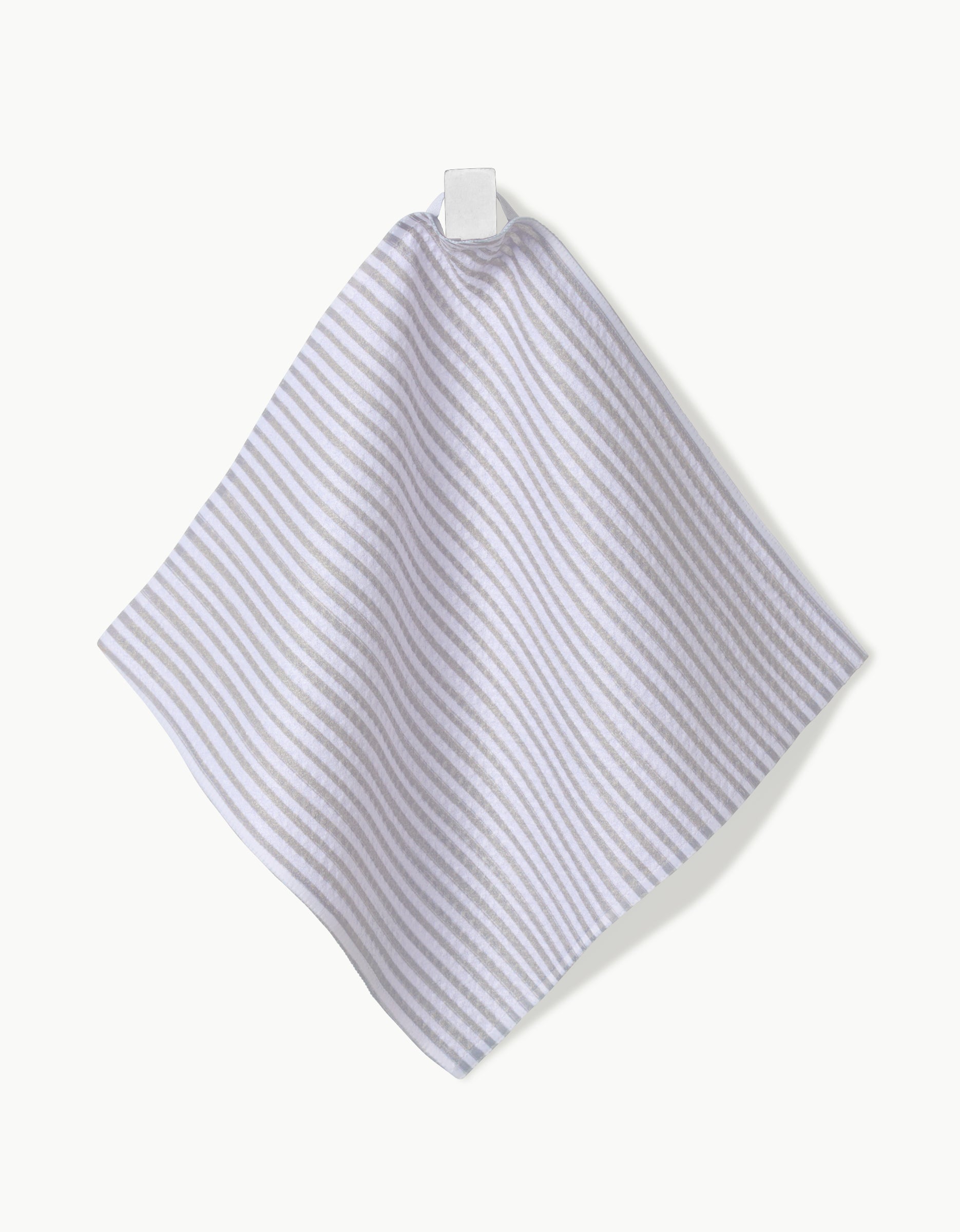 The Kailee Wright À La Carte dishcloth, featuring light gray and white stripes and made from Geoweave fabric, hangs from a white fabric loop against a crisp white background.